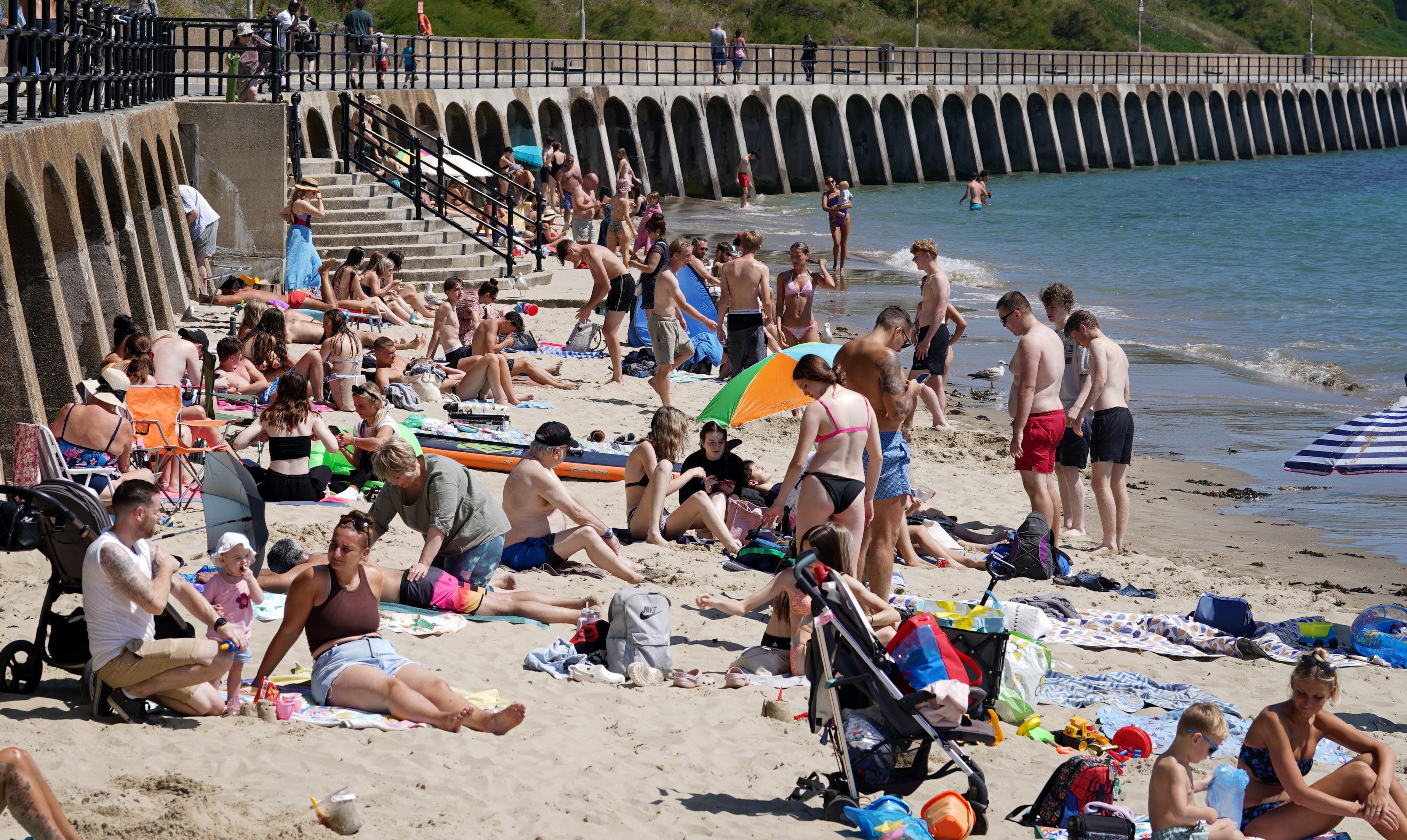 People enjoy the warm weather on Sunny Sands beach in Folkestone, Kent, as the third heatwave of the summer hits the UK and temperatures are expected to remain high into the weekend
