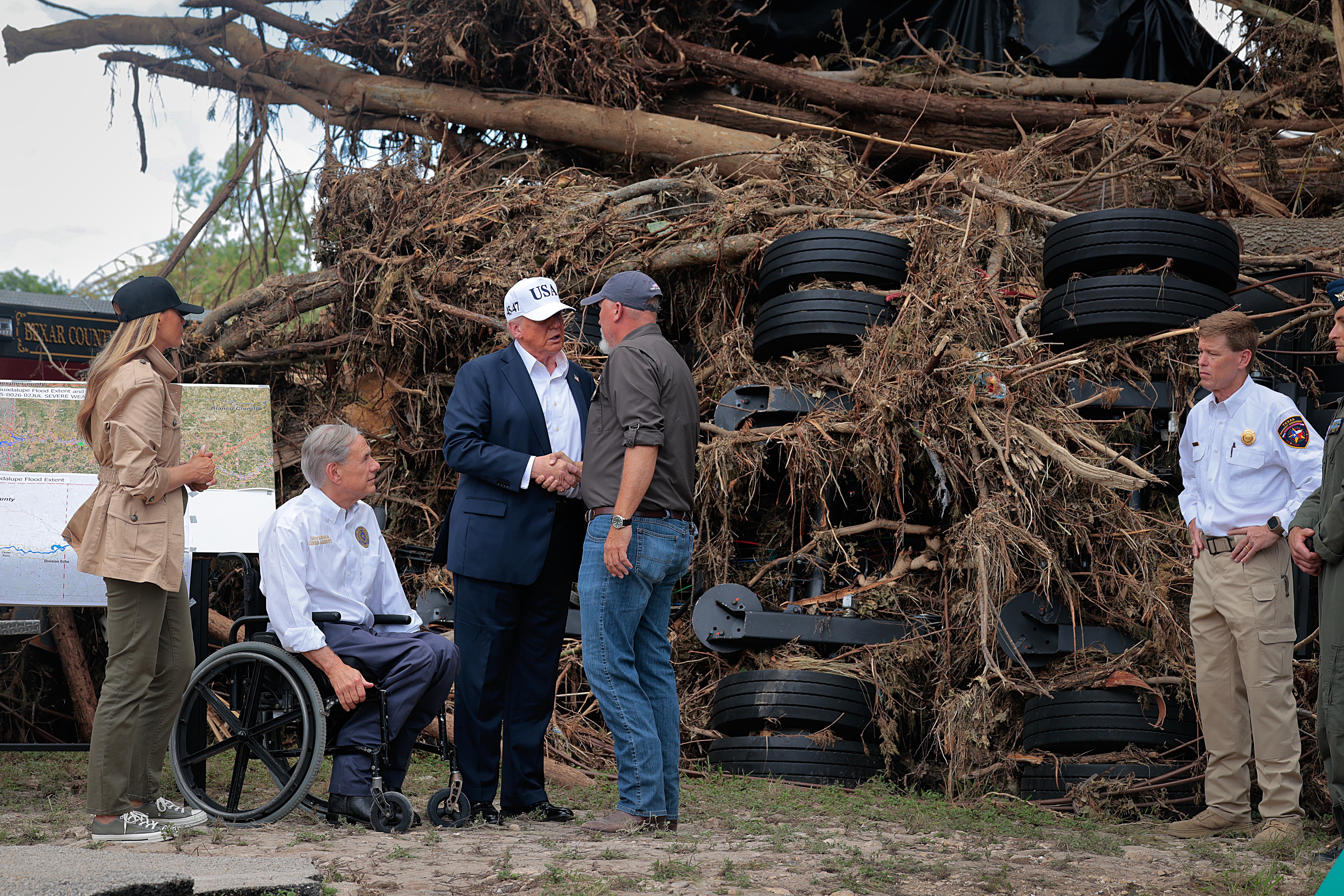 Trump, first lady Melania Trump, and Texas Governor Greg Abbott meet with local emergency services personnel as they survey flood damage along the Guadalupe River