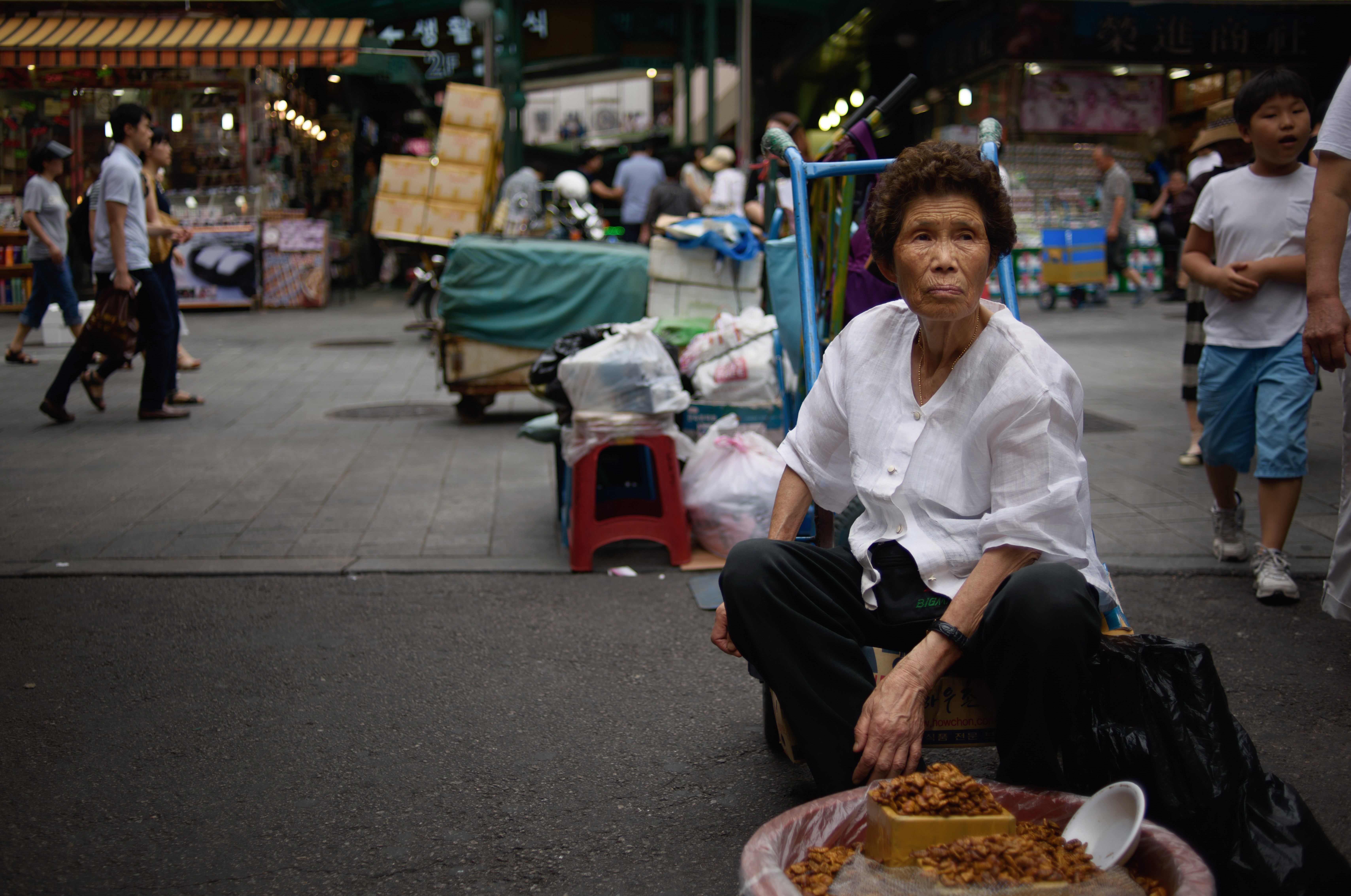 A South Korean vendor sits before a bowl of 'beondegi' or boiled silkworm pupae