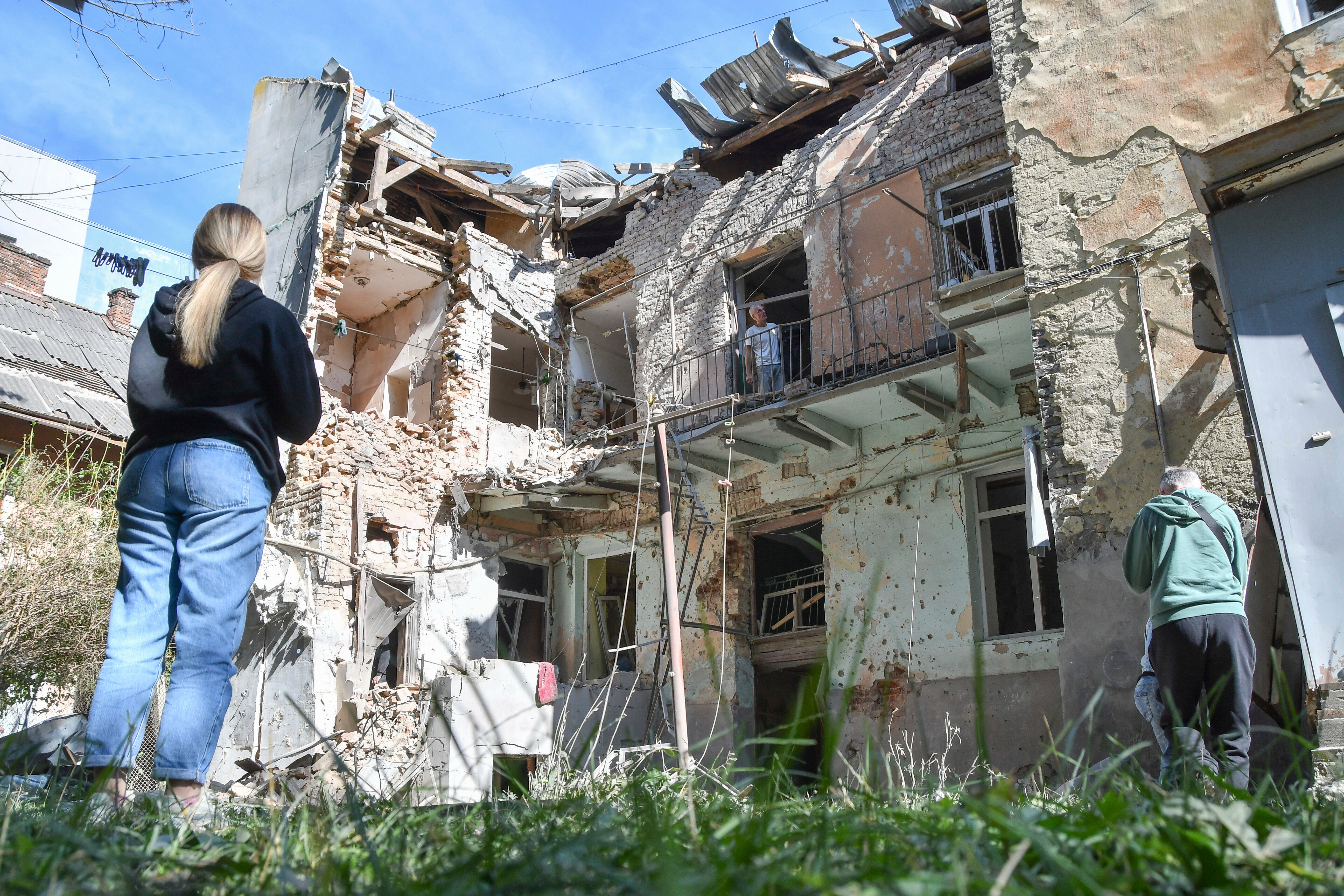People look at a damaged residential building following a Russian air attack in Lviv on Saturday