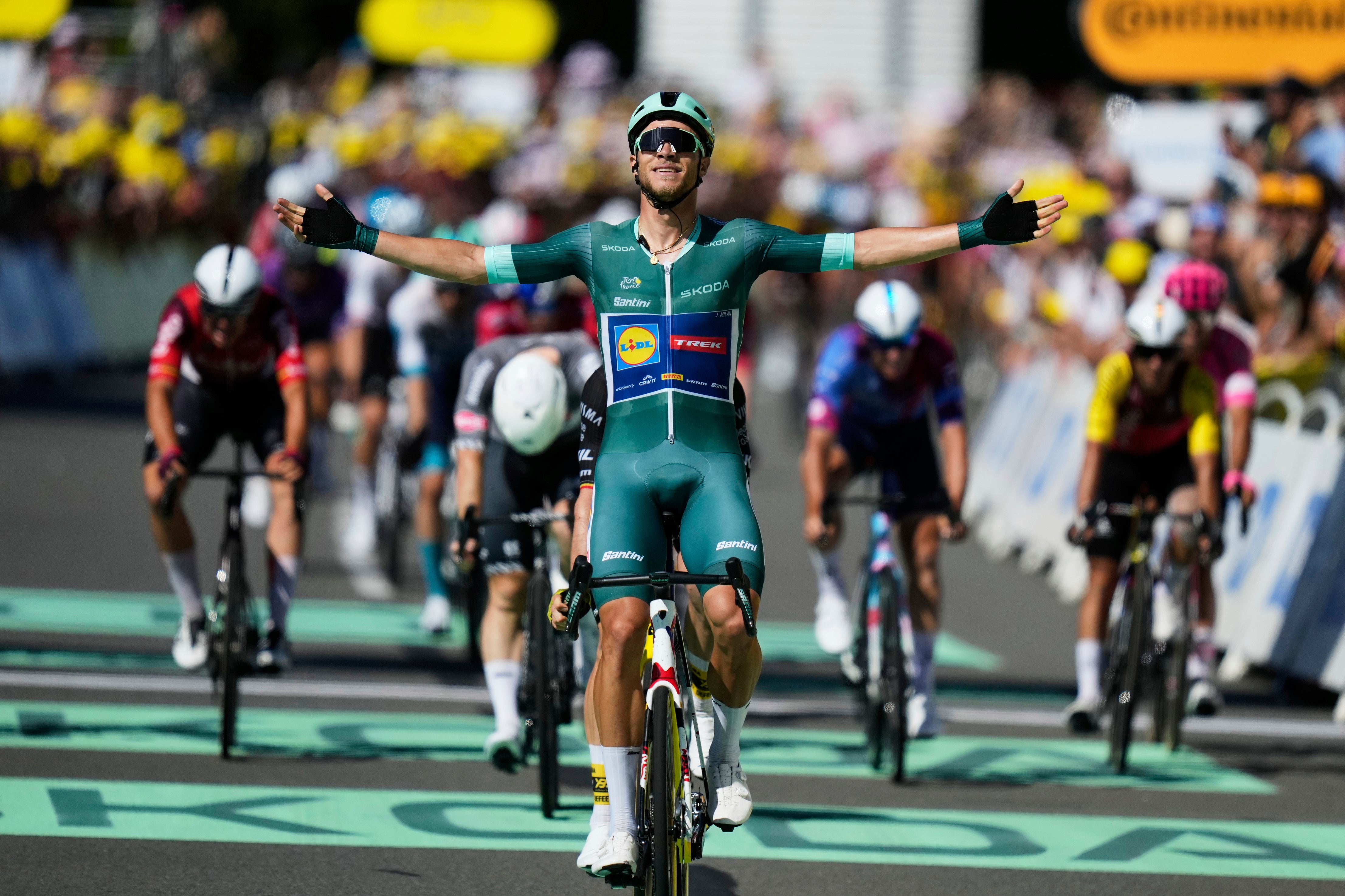 Italy's Jonathan Milan, wearing the best sprinter's green jersey, celebrates as he crosses the finish line to win the eighth stage