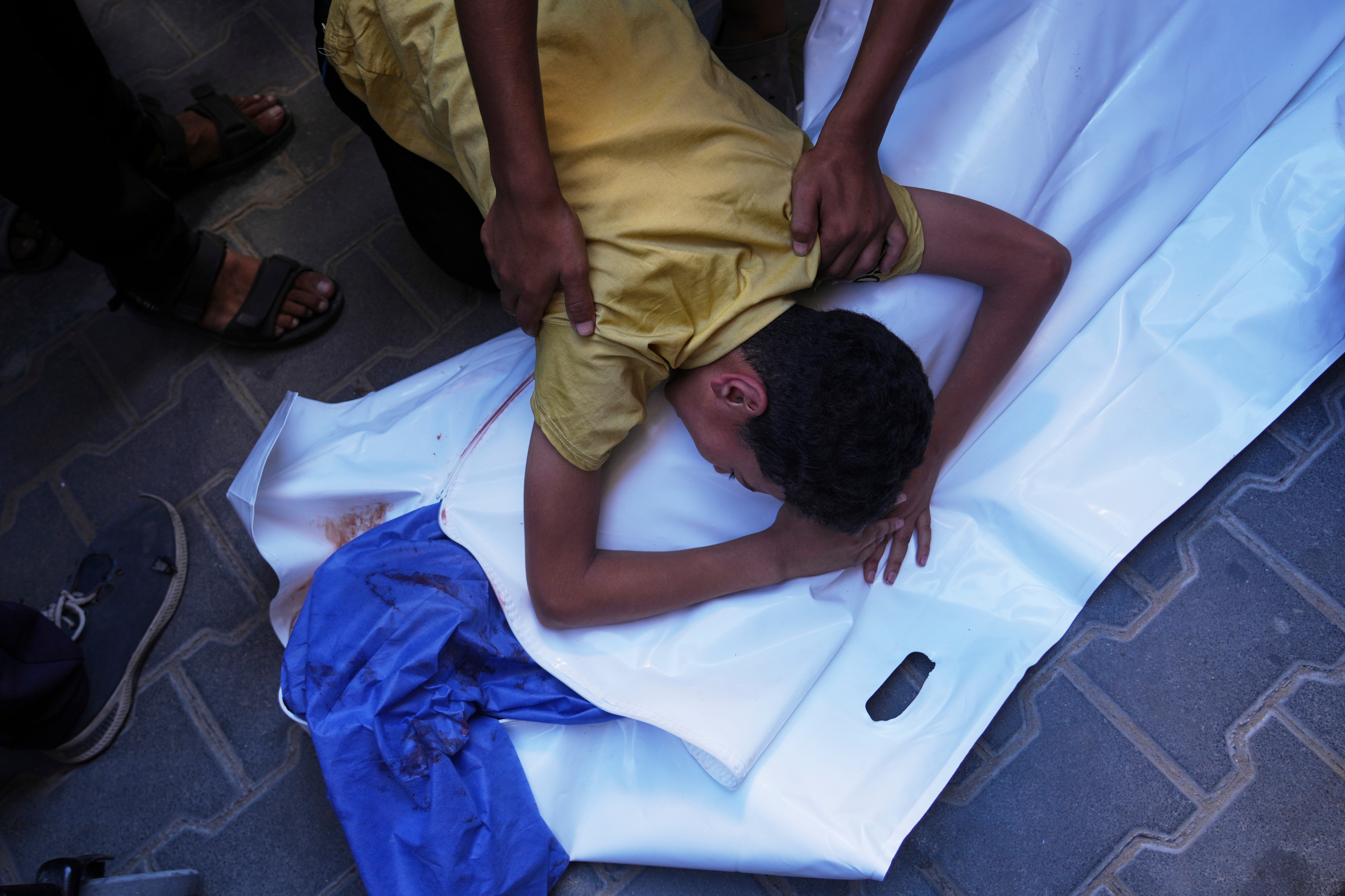 A Palestinian boy mourns over the body of his 12-year-old friend, Abdullah Ahmed, who was killed in an Israeli strike that targeted a drinking water distribution point