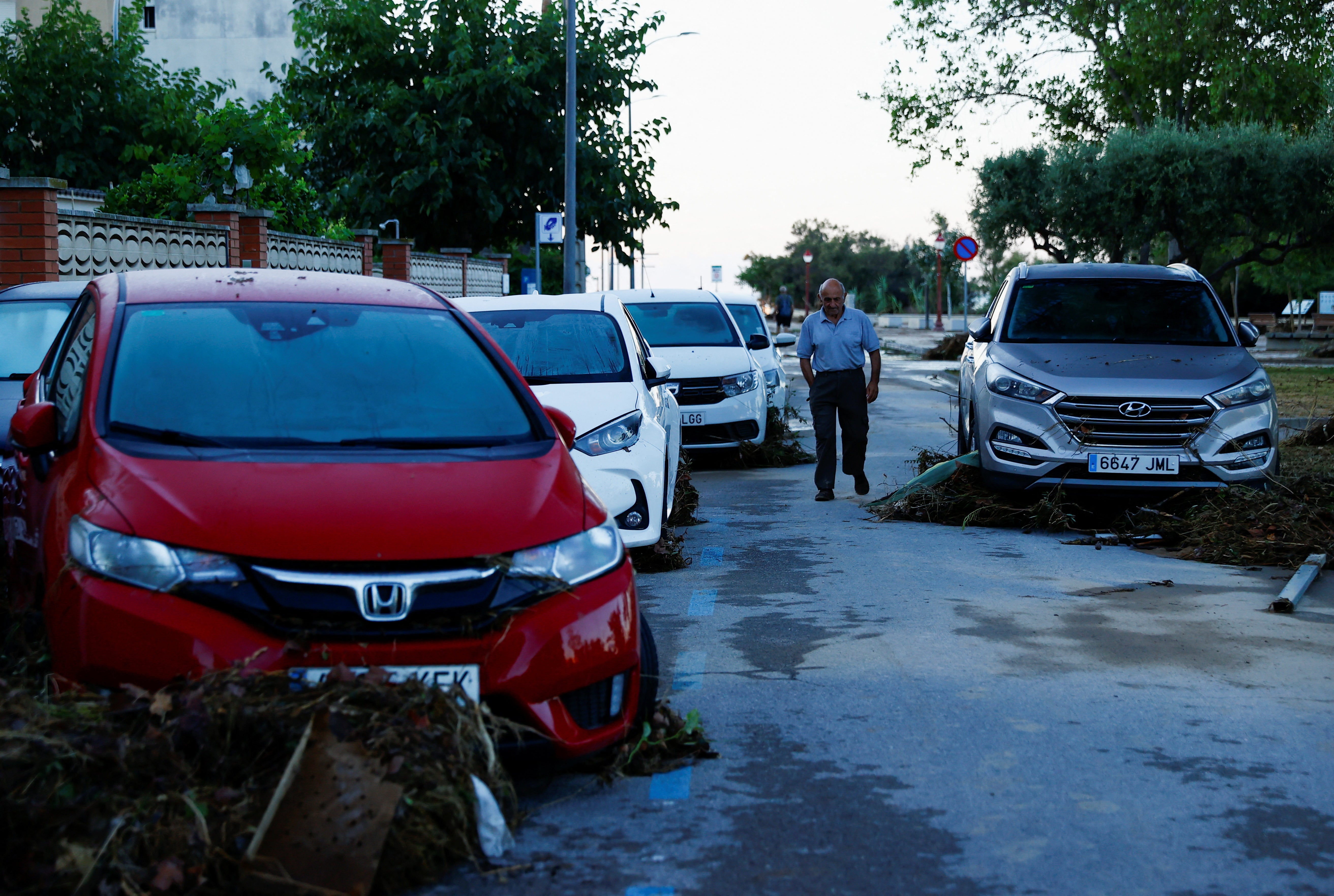 A man walks by damaged cars in Cubelles following flash flooding over the weekend