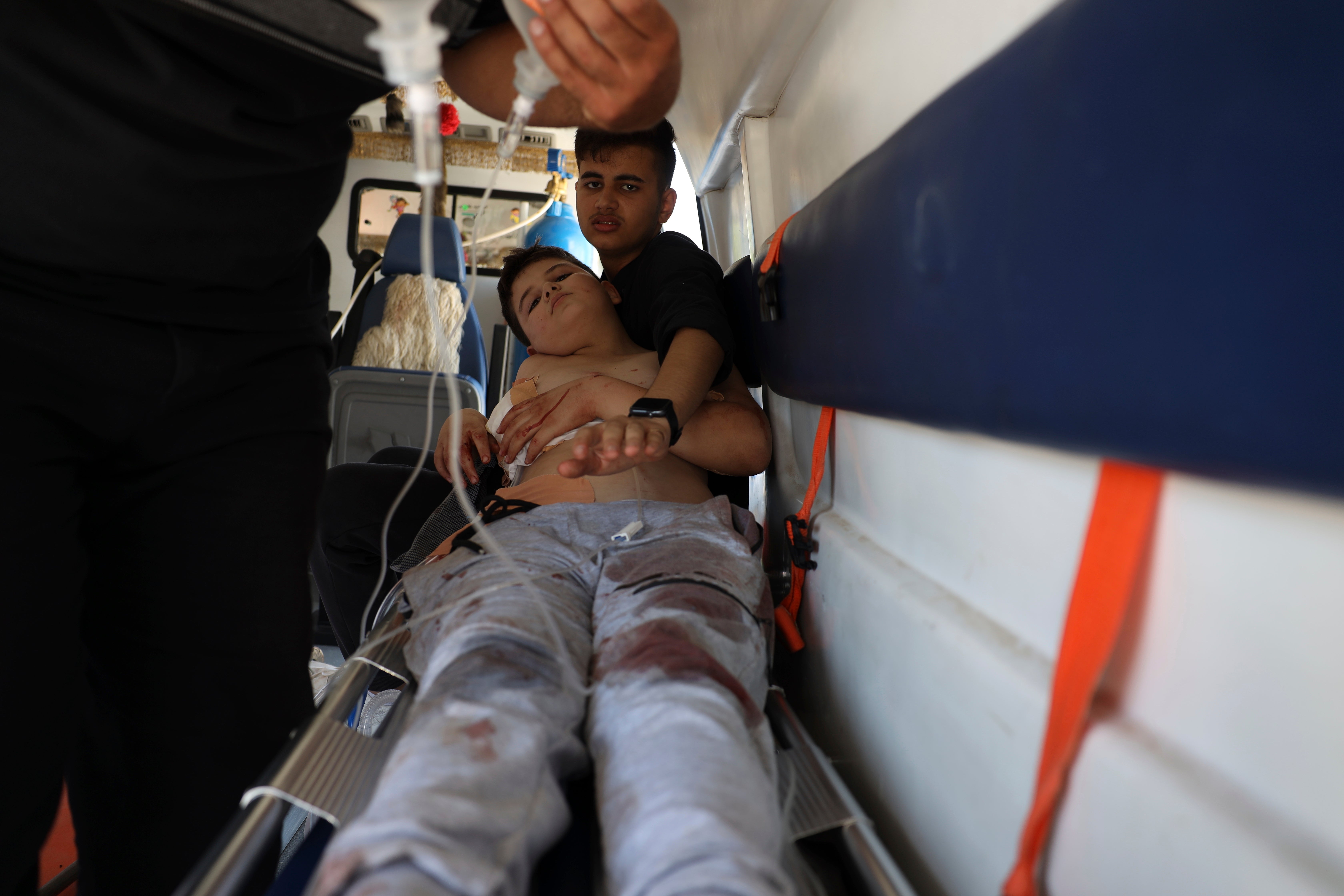 A boy who was injured in Sweida city during clashes between the Syrian government forces and Druze militias, lies inside an ambulance in Busra al-Harir village