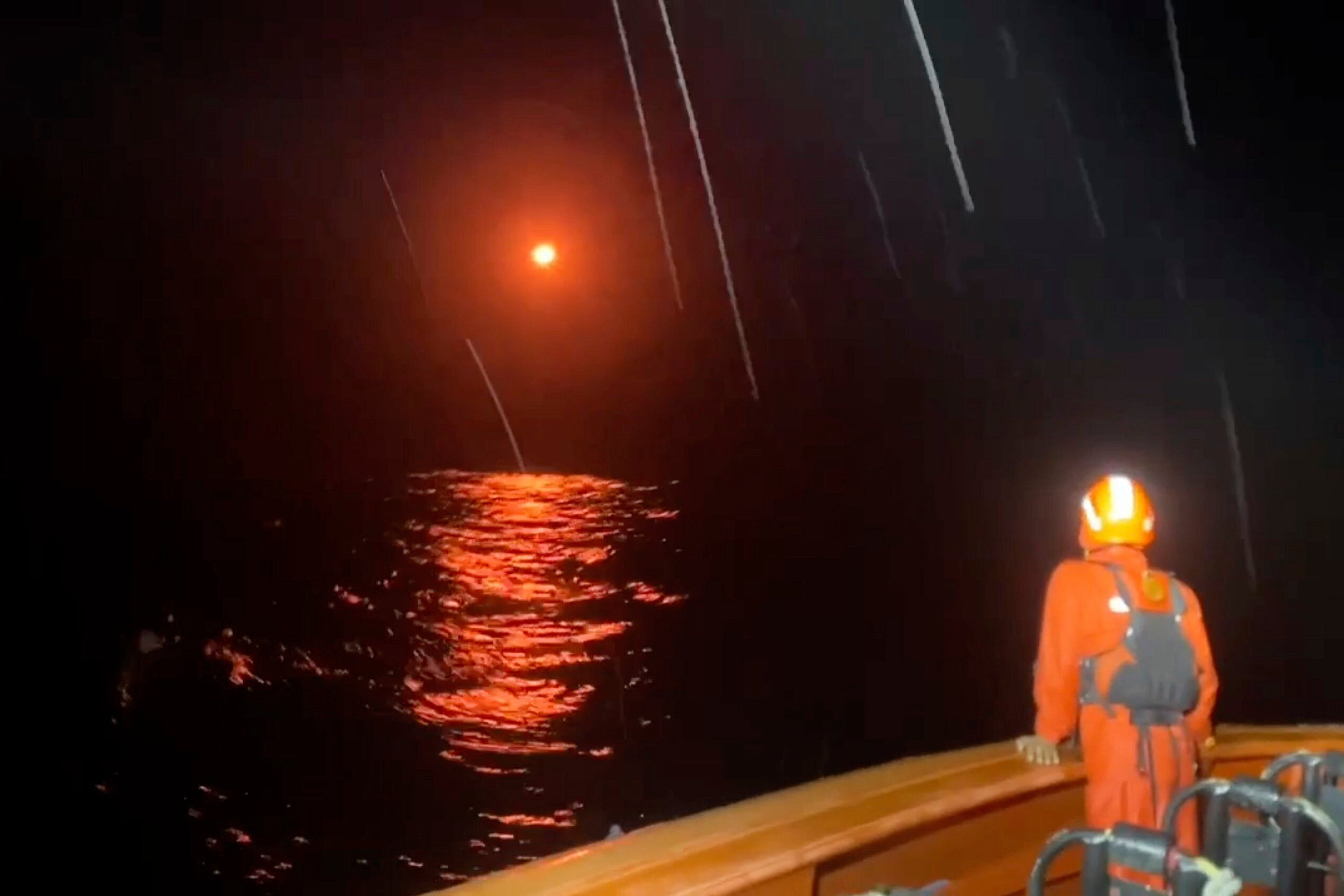 A flare lights up the sky as rescuers search for survivors after a boat capsized on July 14 in Indonesia