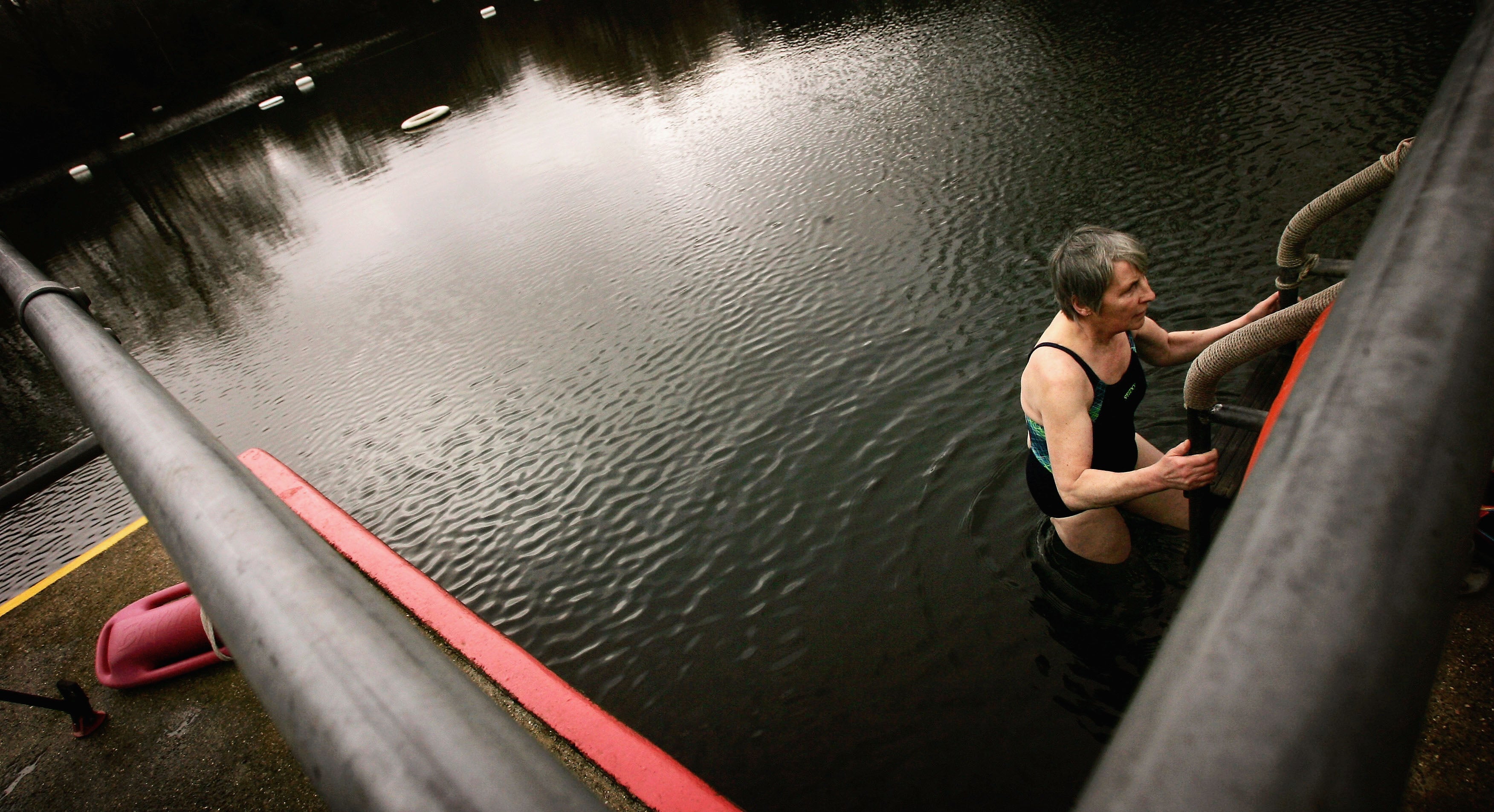 A woman climbing out of Hampstead Heath’s ladies’ pond in winter