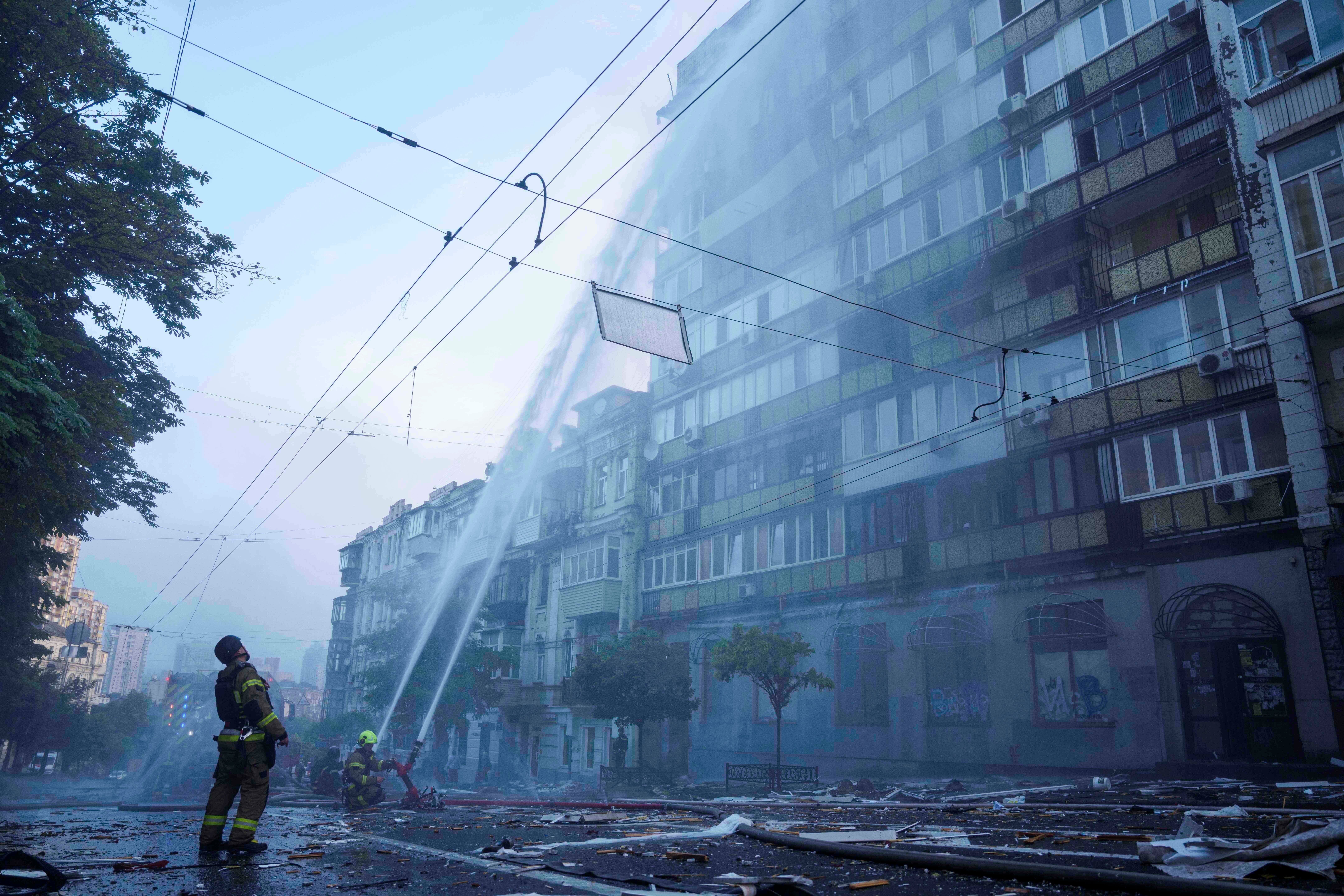Rescue workers try to put out a fire at an apartment building heavily damaged by a Russian strike in Kyiv, Ukraine