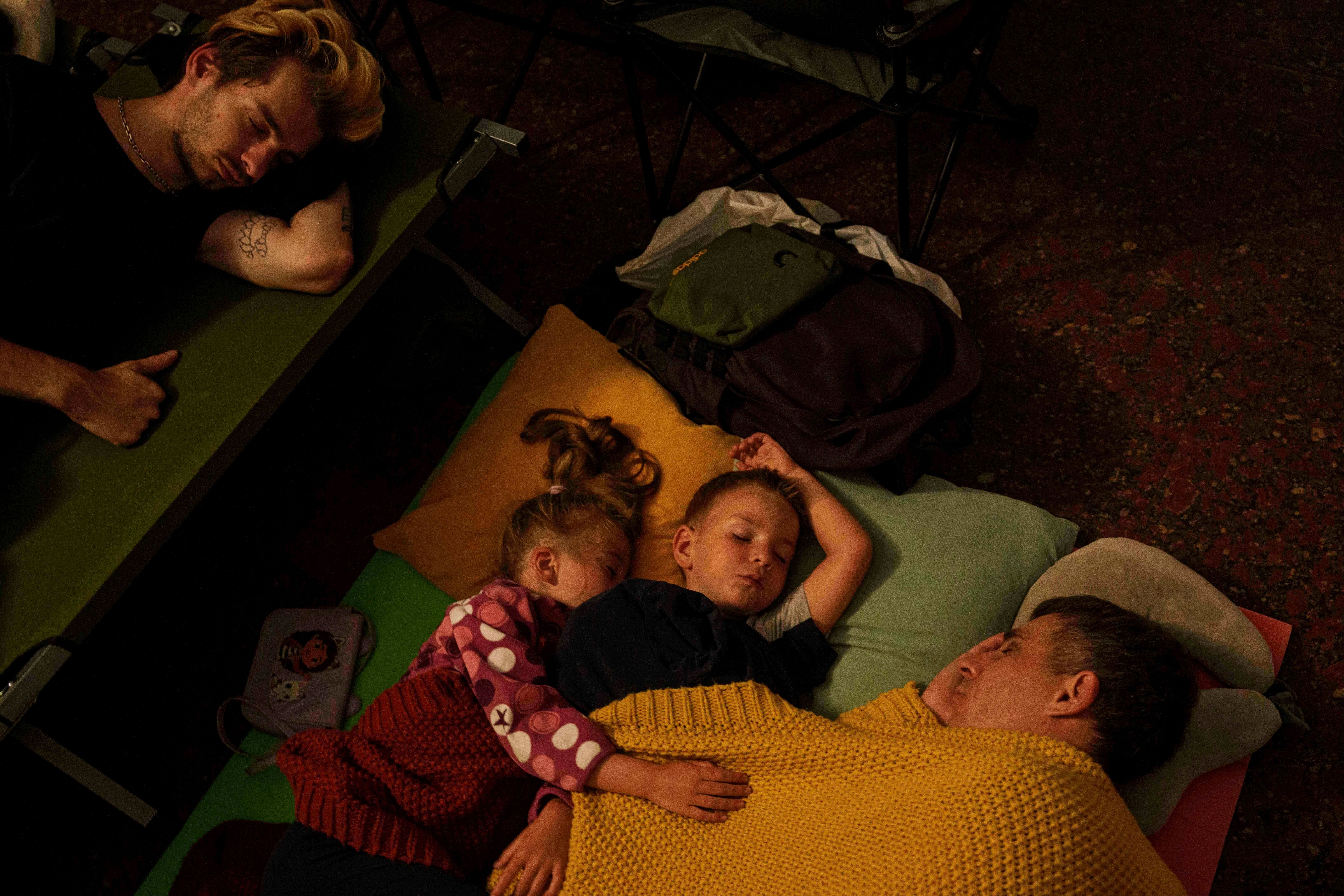 A family sleeps in a metro station as they take cover during a Russian attack on Kyiv, Ukraine,