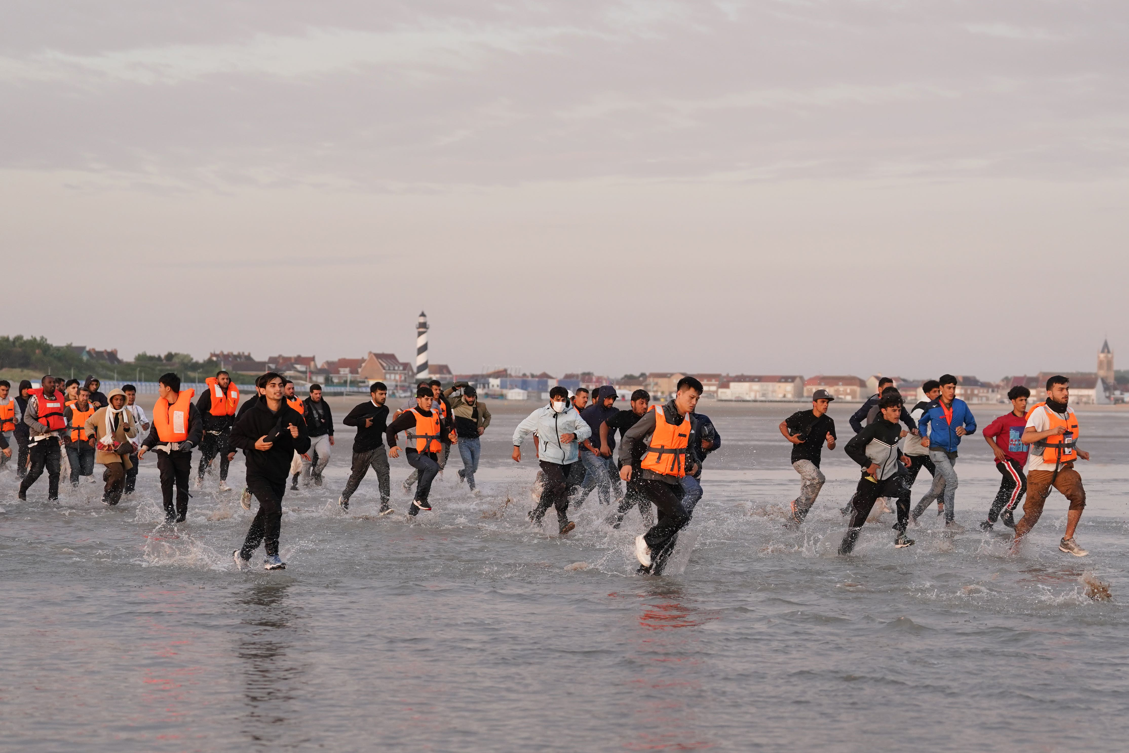 People thought to be migrants run across the beach in Gravelines, France, in a bid to board a small boat (Gareth Fuller/PA)