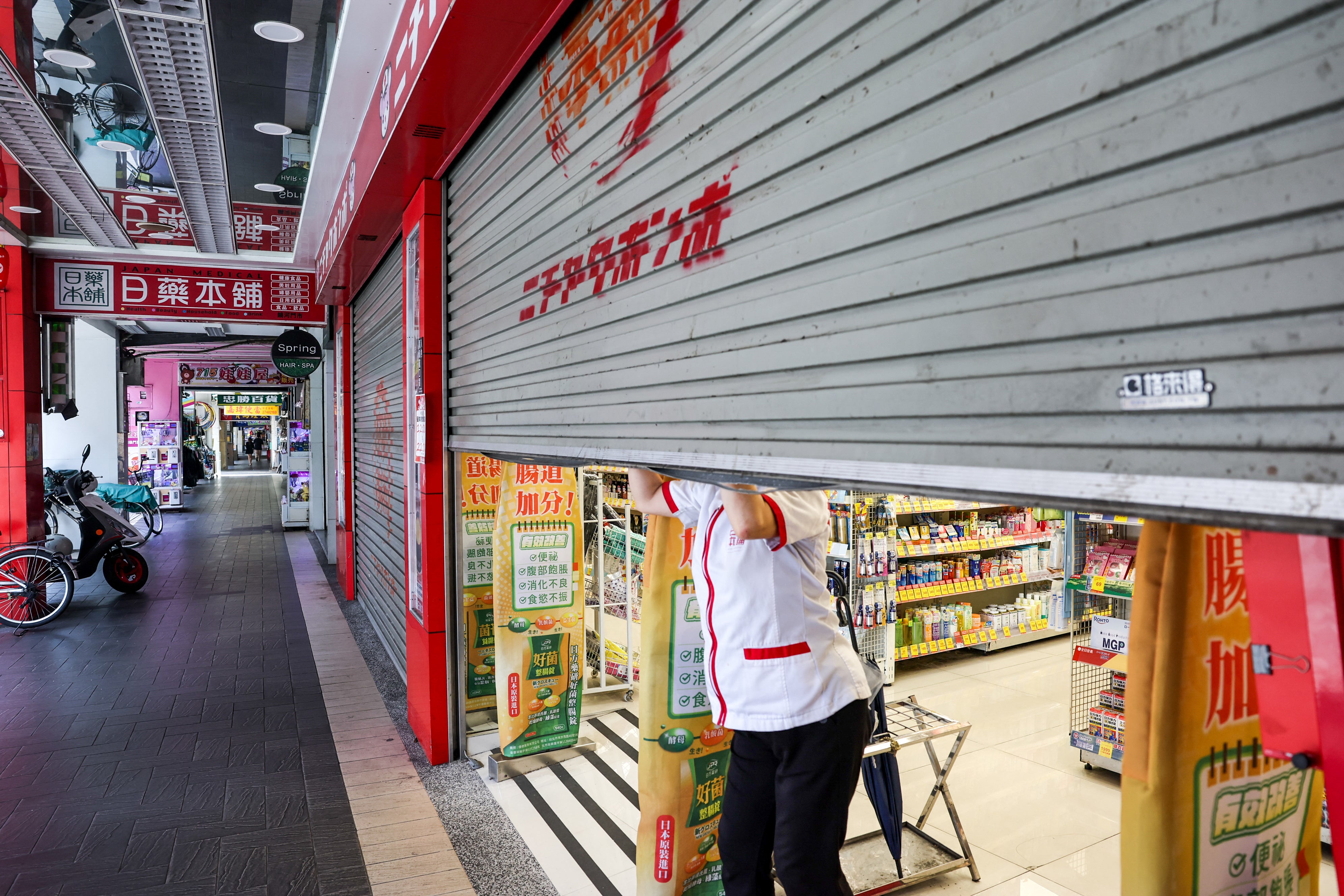 An employee shutters a shop before an air raid drill coinciding with the Han Kuang military exercises in Taipei