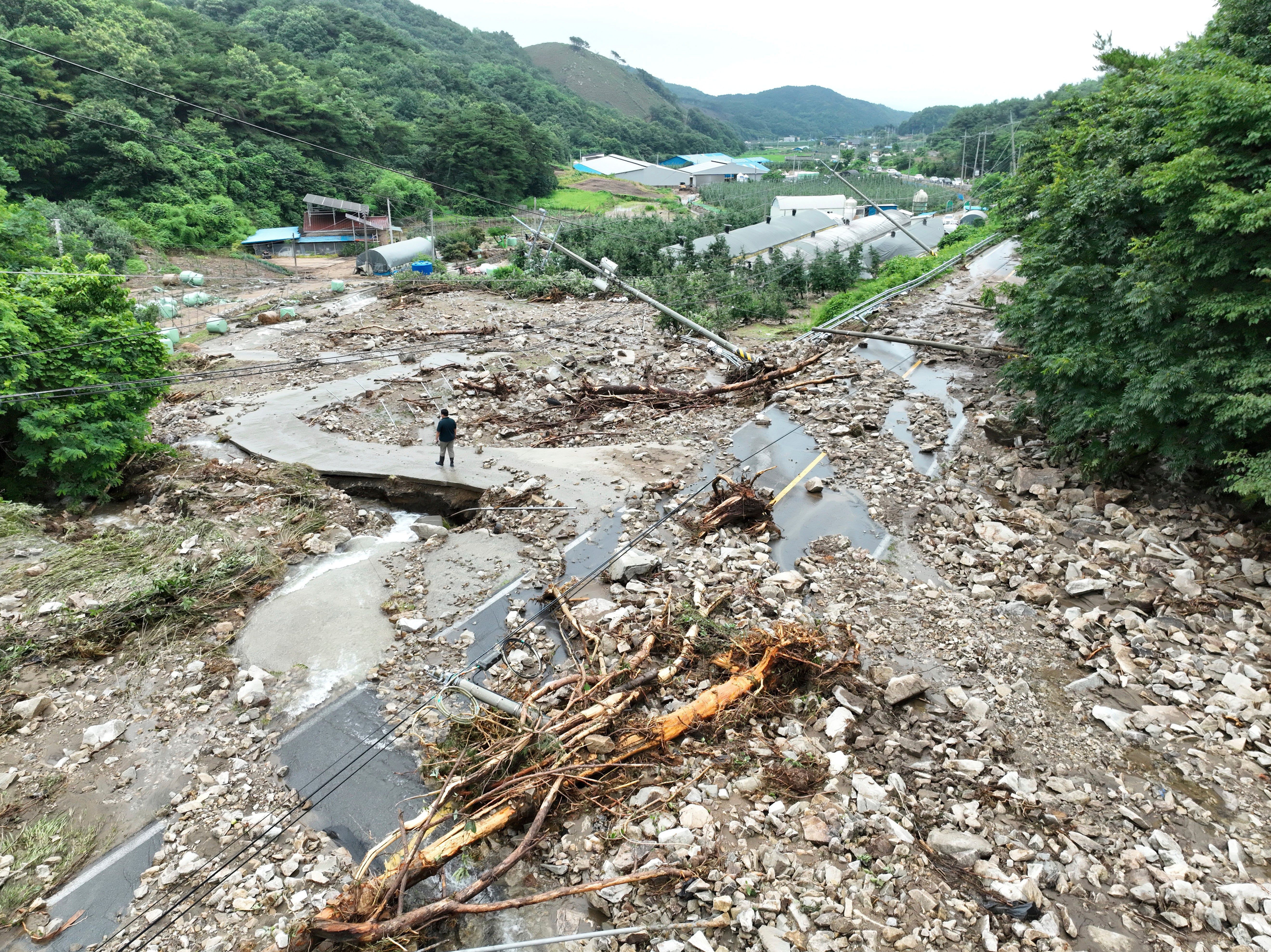 A road is covered with earth and rocks brought by a nearby landslide due to heavy rain at a village in Yesan, South Korea