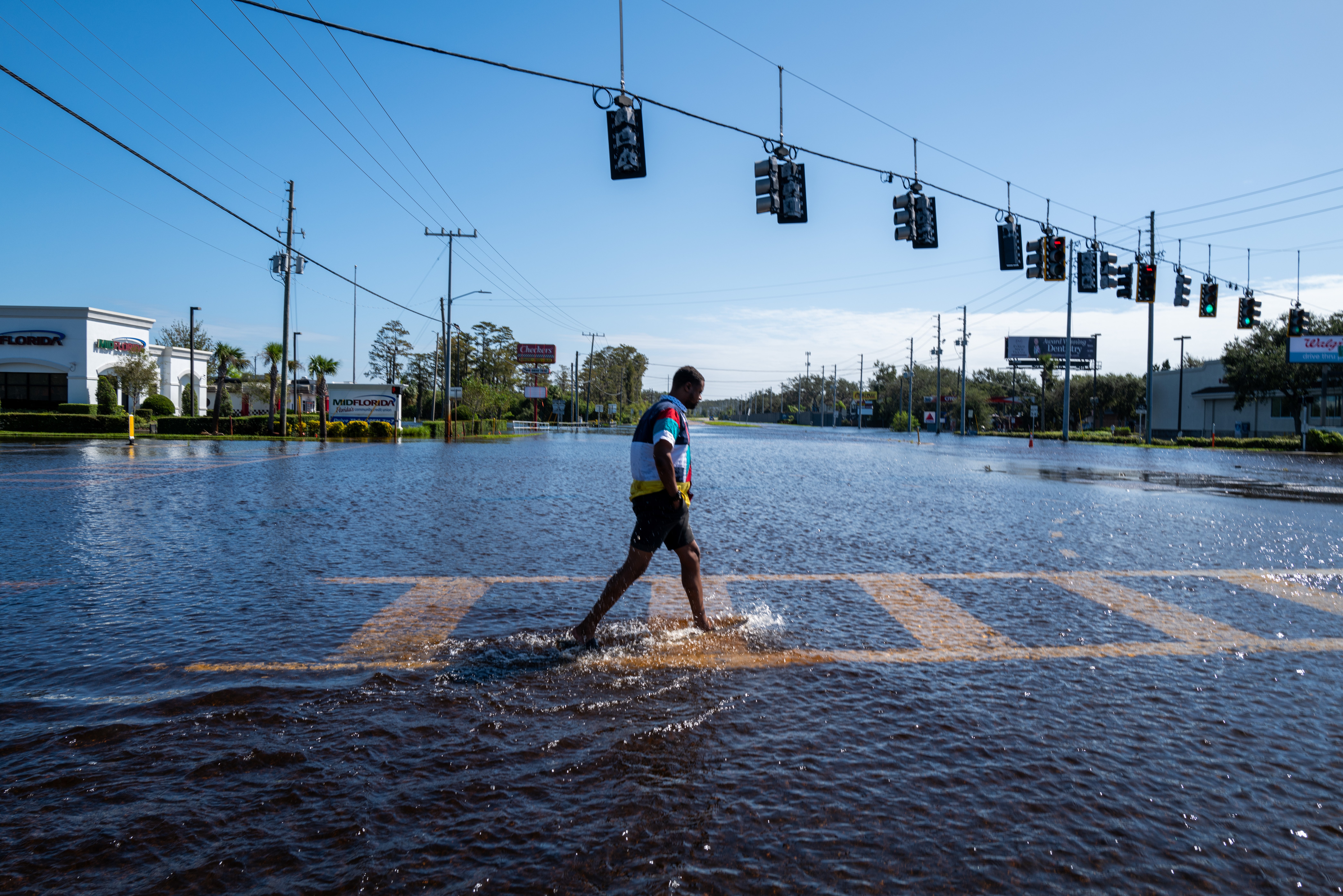 A man walks through a flooded street after Hurricane Milton in Port Richey, Florida, last October. Climate change-induced flooding is increasing chances for exposure to the flesh-eating bacteria