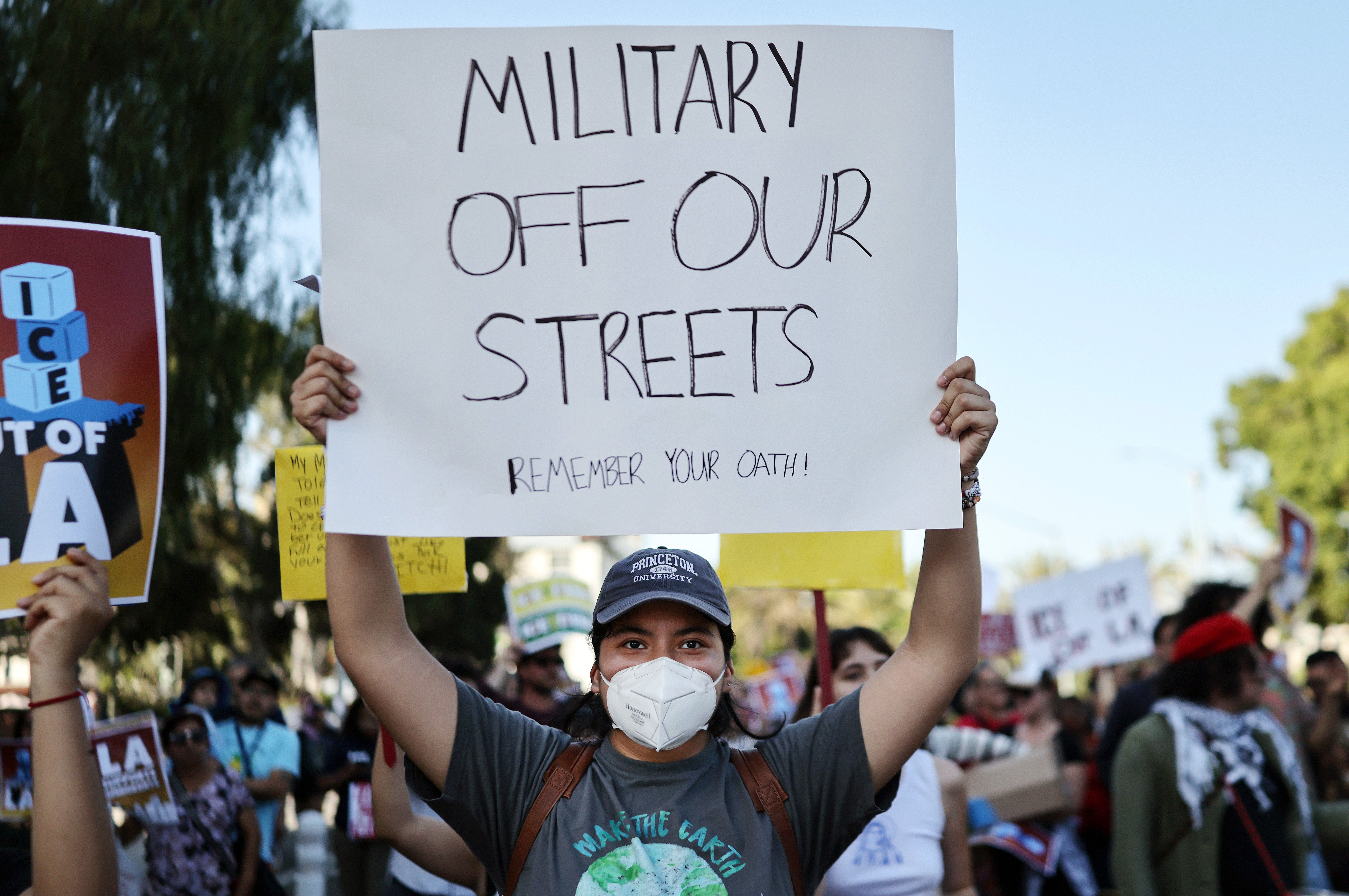 A Los Angeles protester carries a sign that reads, 'MILITARY OFF OUR STREETS.' Governor Gavin Newsom attempted to sue the Trump administration to stop them from commandeering National Guard troops in the region