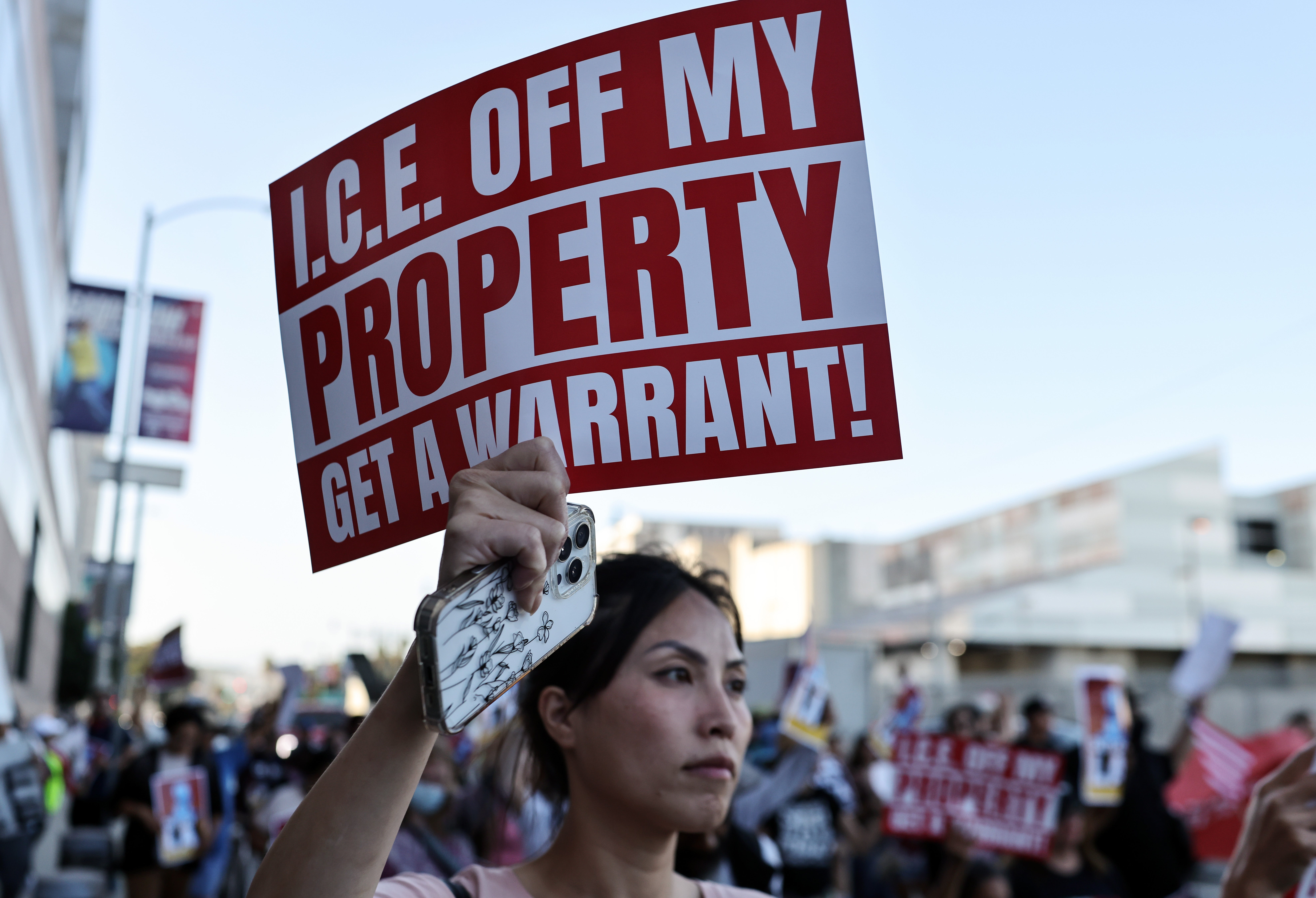 A Los Angeles protester holds a sign that reads, 'ICE OFF MY PROPERTY GET A WARRANT!' The anti-ICE protests erupted early last month