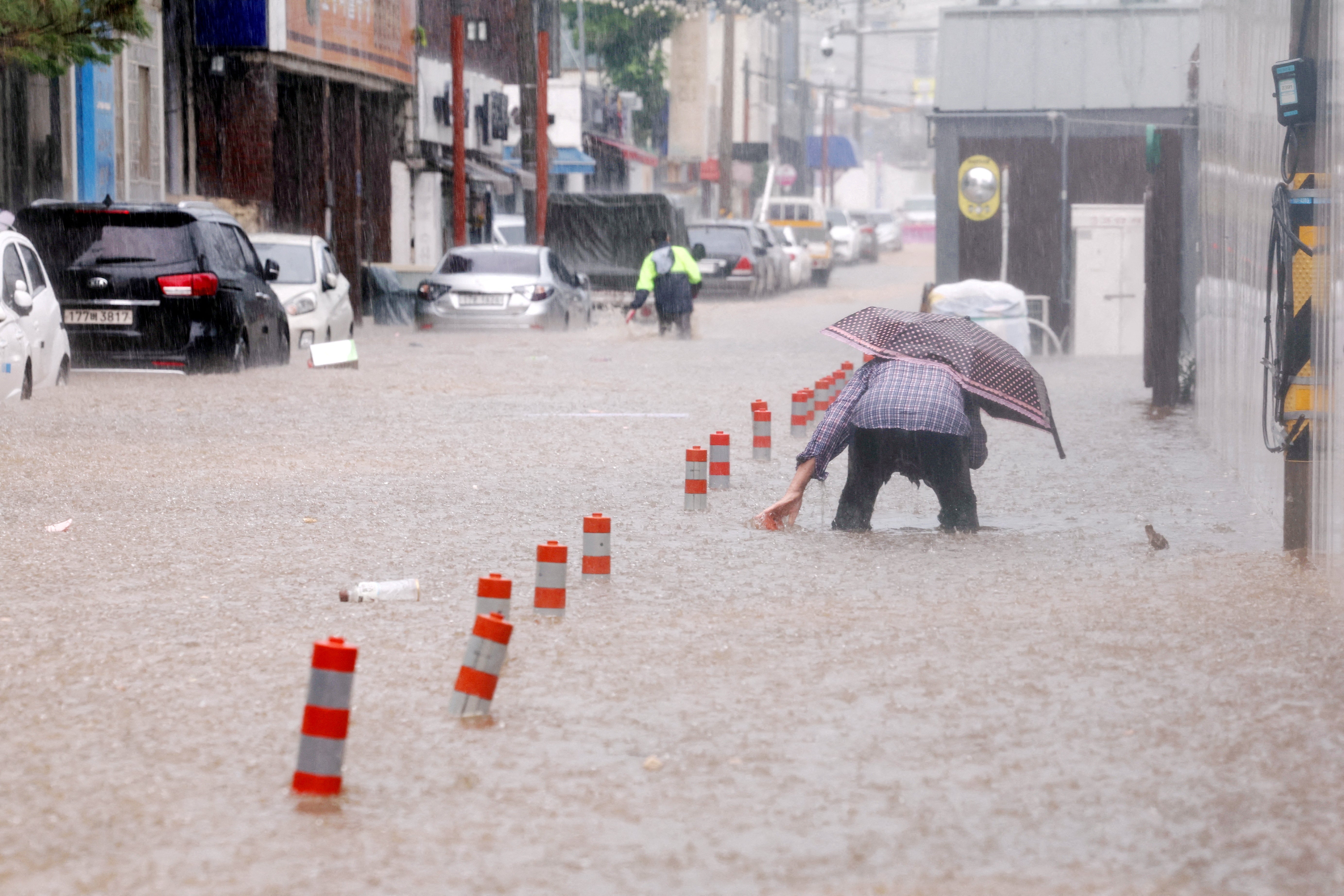 A man makes his way through a flooded street, caused by torrential rain, in Gwangju, South Korea