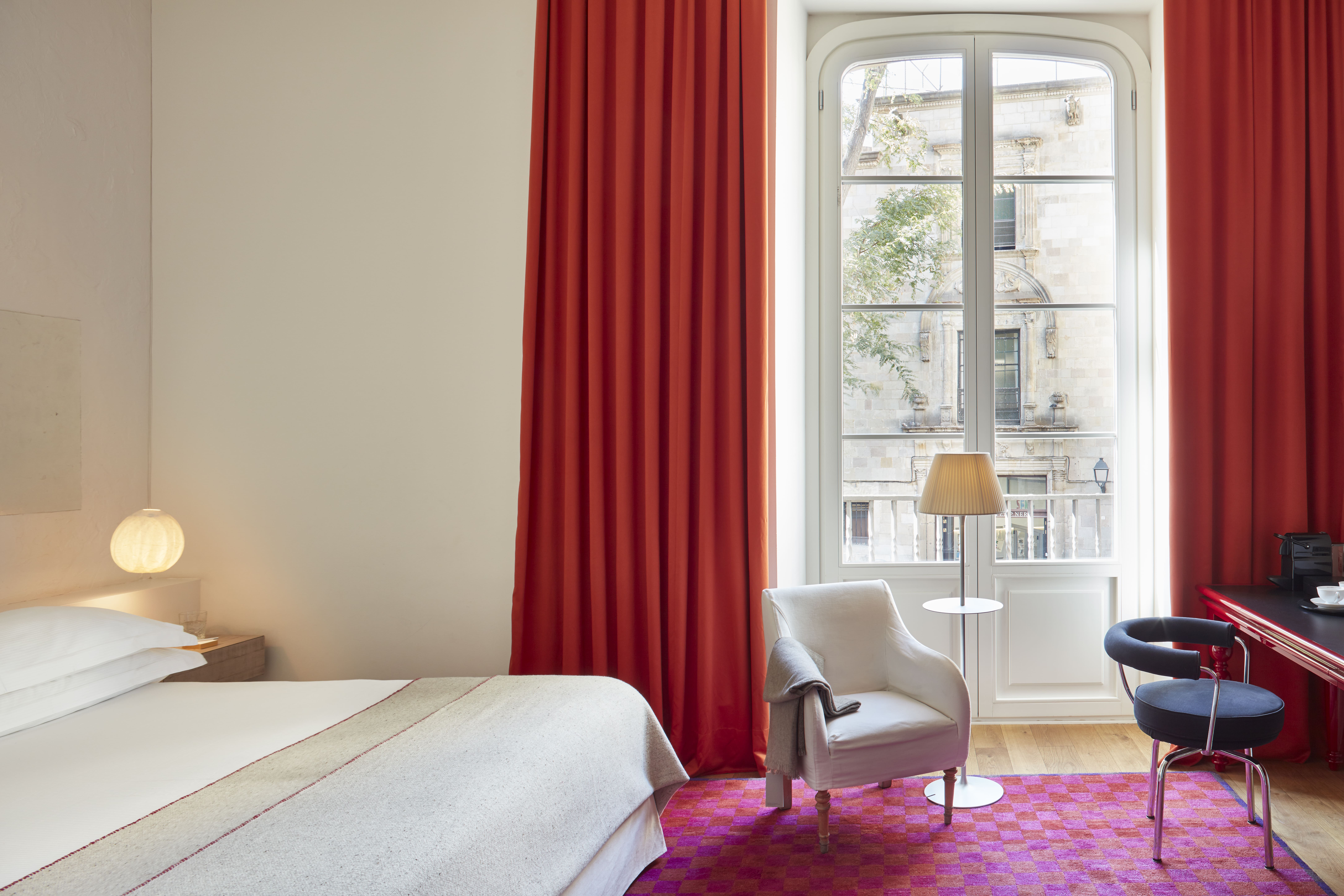 Hotel Neri brings a boutique feel to its rooms with hot pink rugs and long drapes