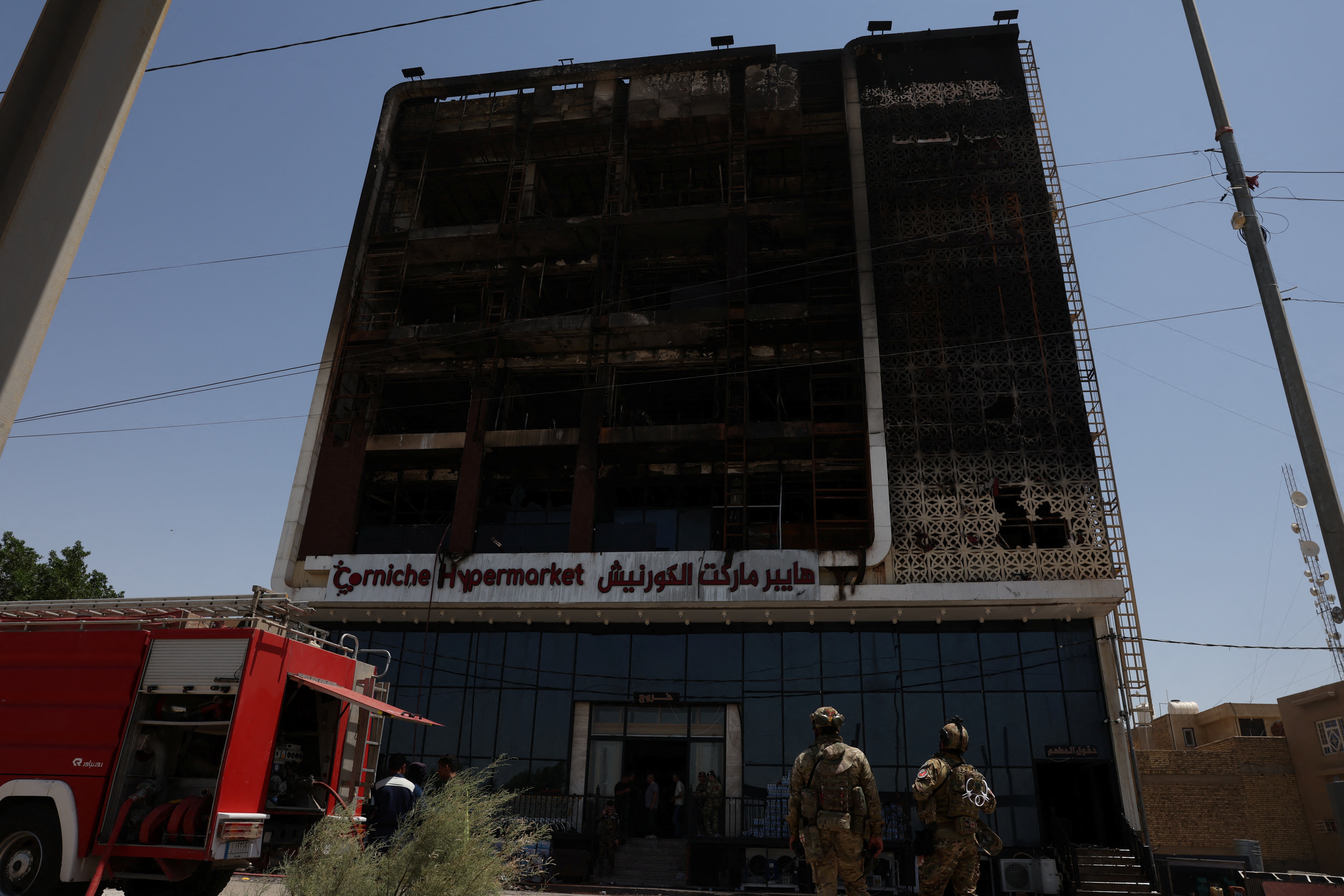 A fire truck stands next to the wreckage of a five-storey shopping center, after a massive overnight fire killed dozens of people, in al-Kut, Wasit province, Iraq