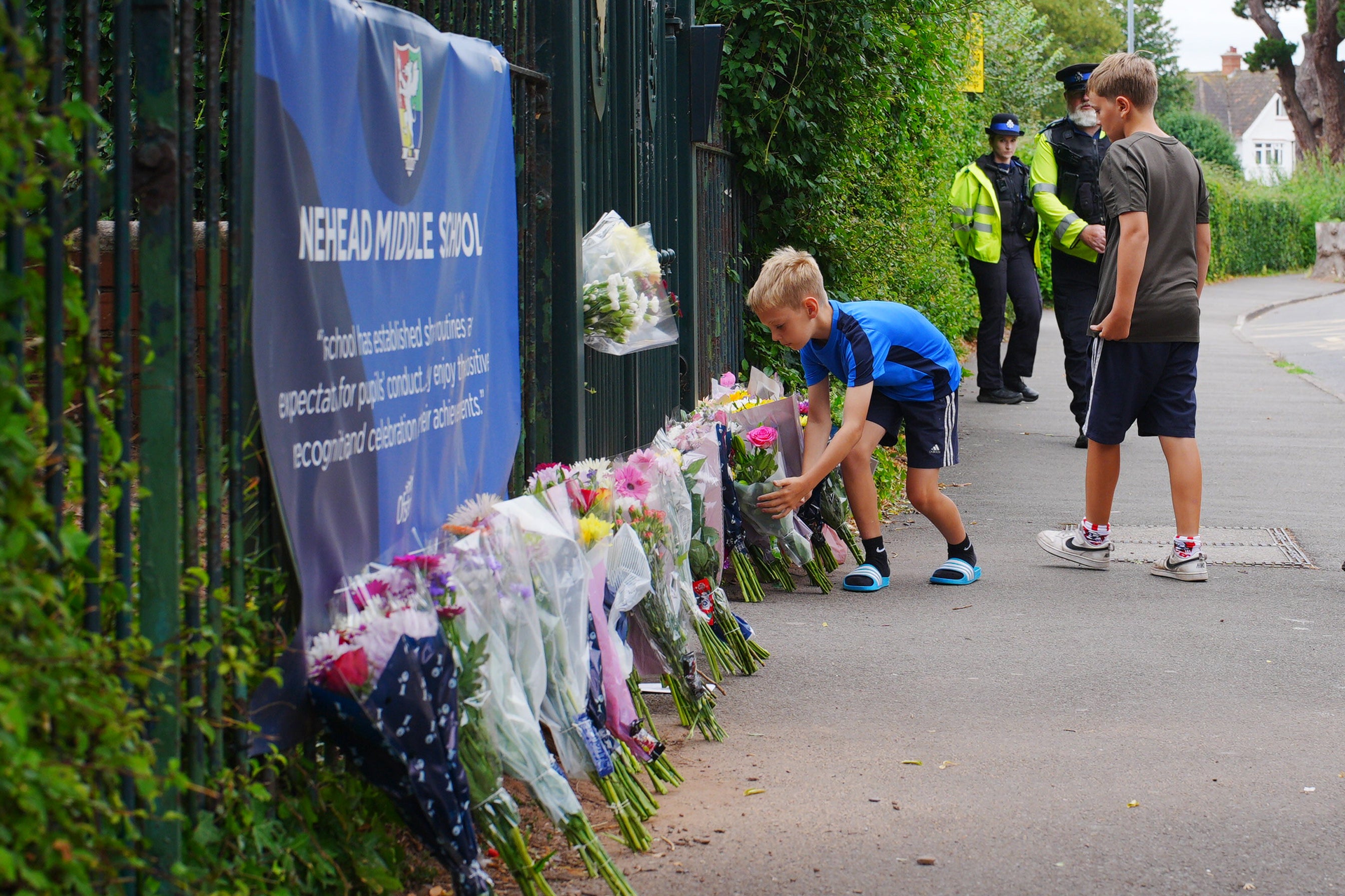 Two boys laid flowers with the floral tributes at the entrance to the Minehead Middle School in Minehead, Somerset