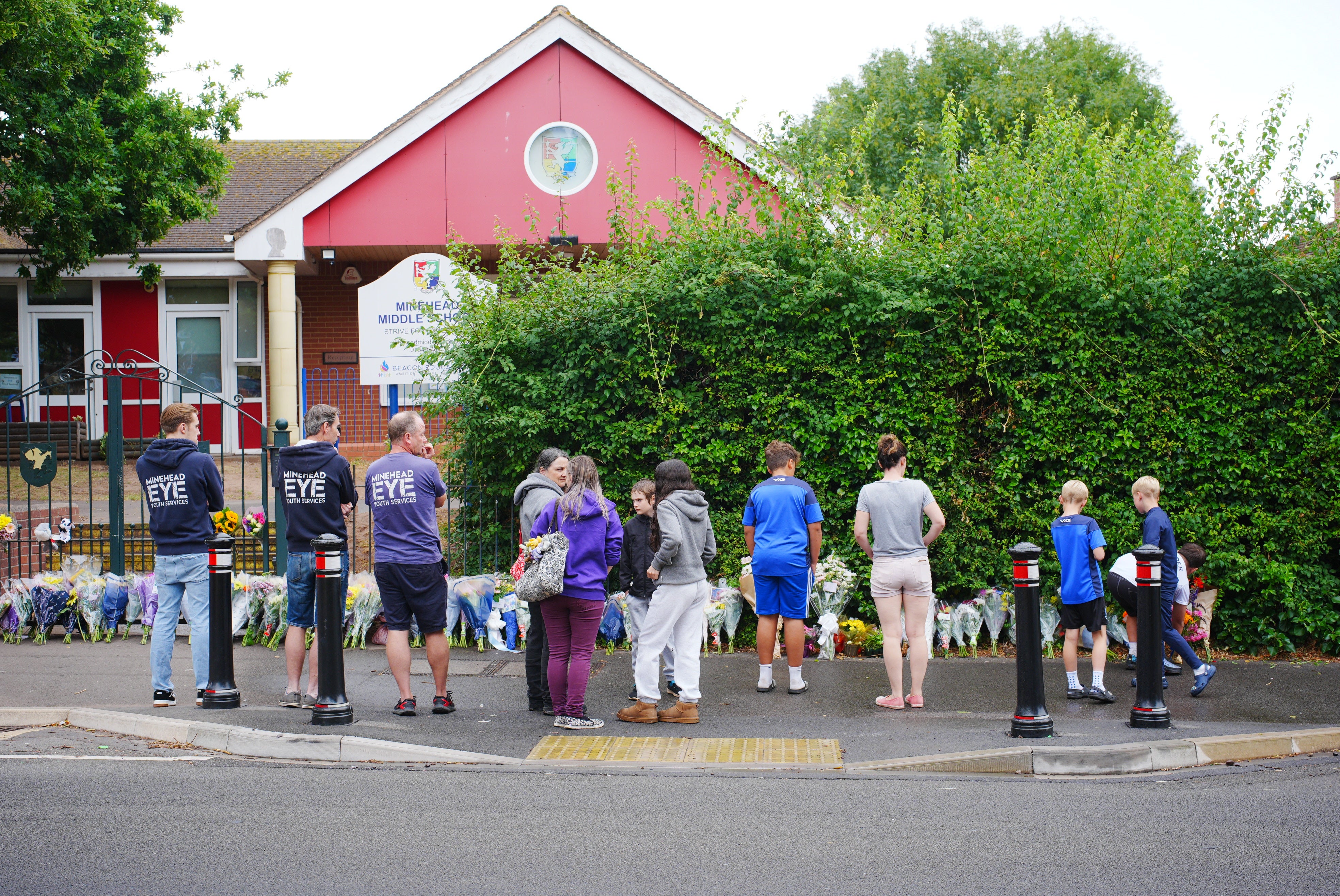 People look at the floral tributes at the entrance to Minehead Middle School