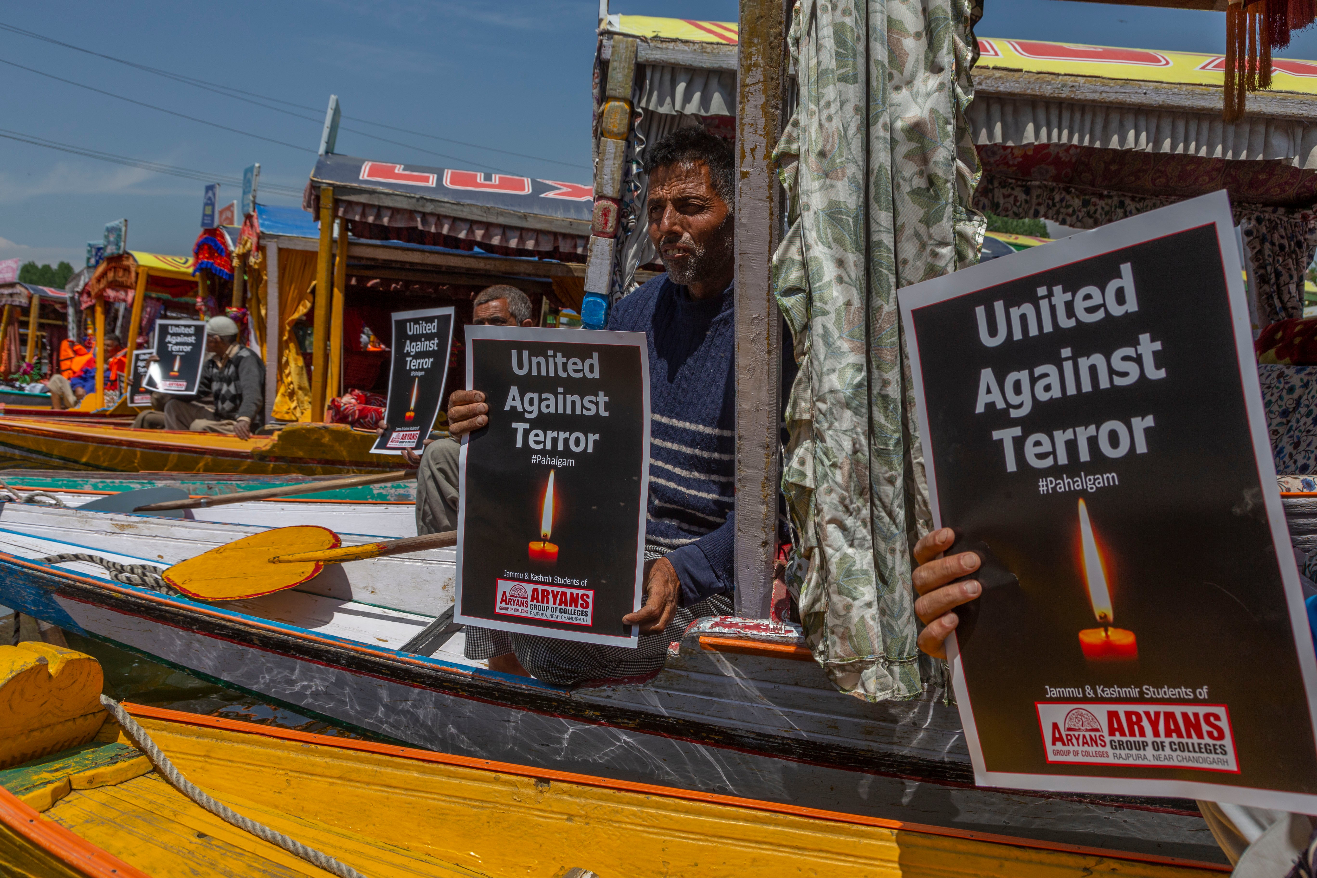 Kashmiri boatmen hold placards handed out by students during a protest organised by them, following an attack on Indian tourists by gunmen on 24 April 2025 in Srinagar