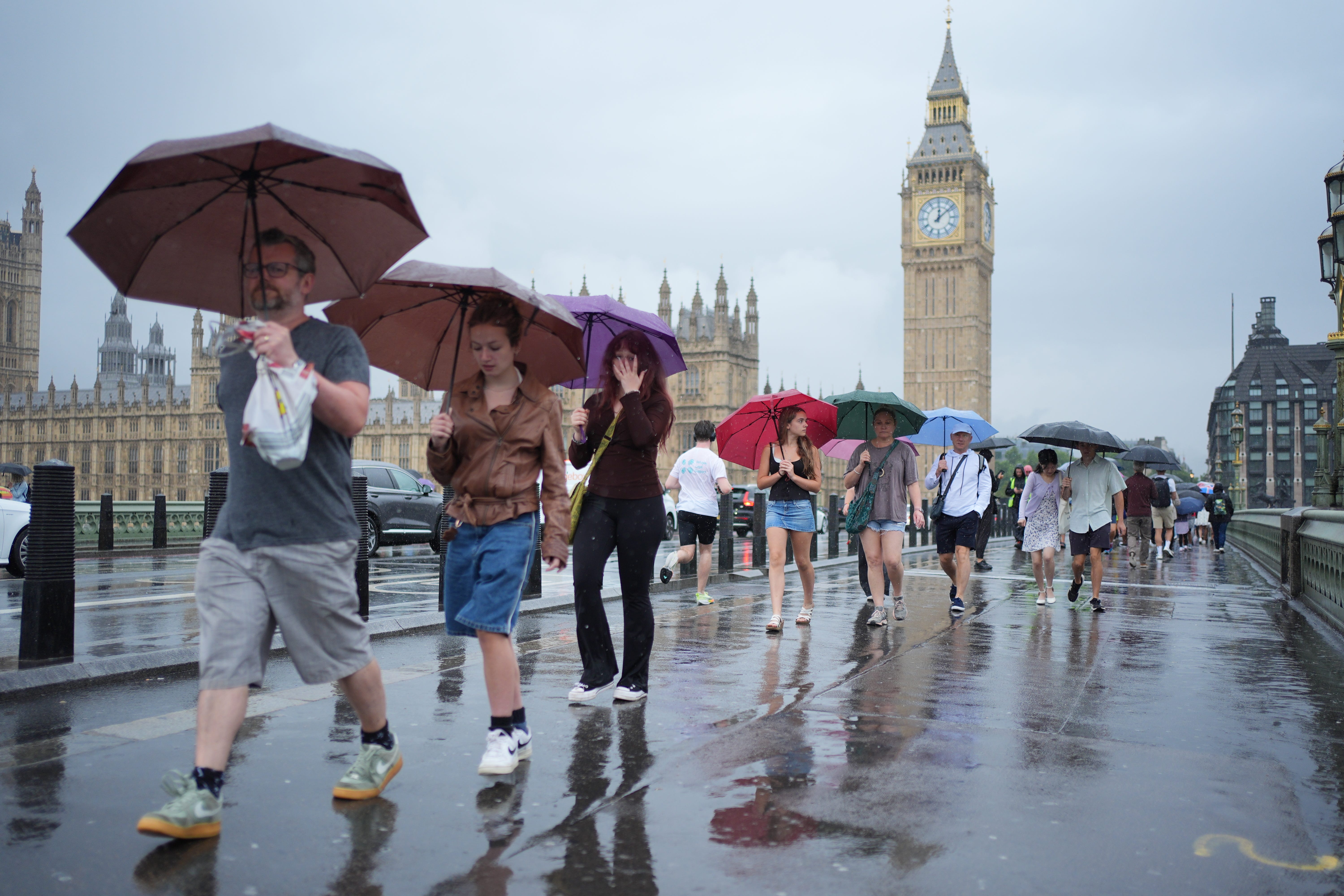 People using umbrellas whilst walking in the rain on Westminster Bridge, in London (Yui Mok/PA)
