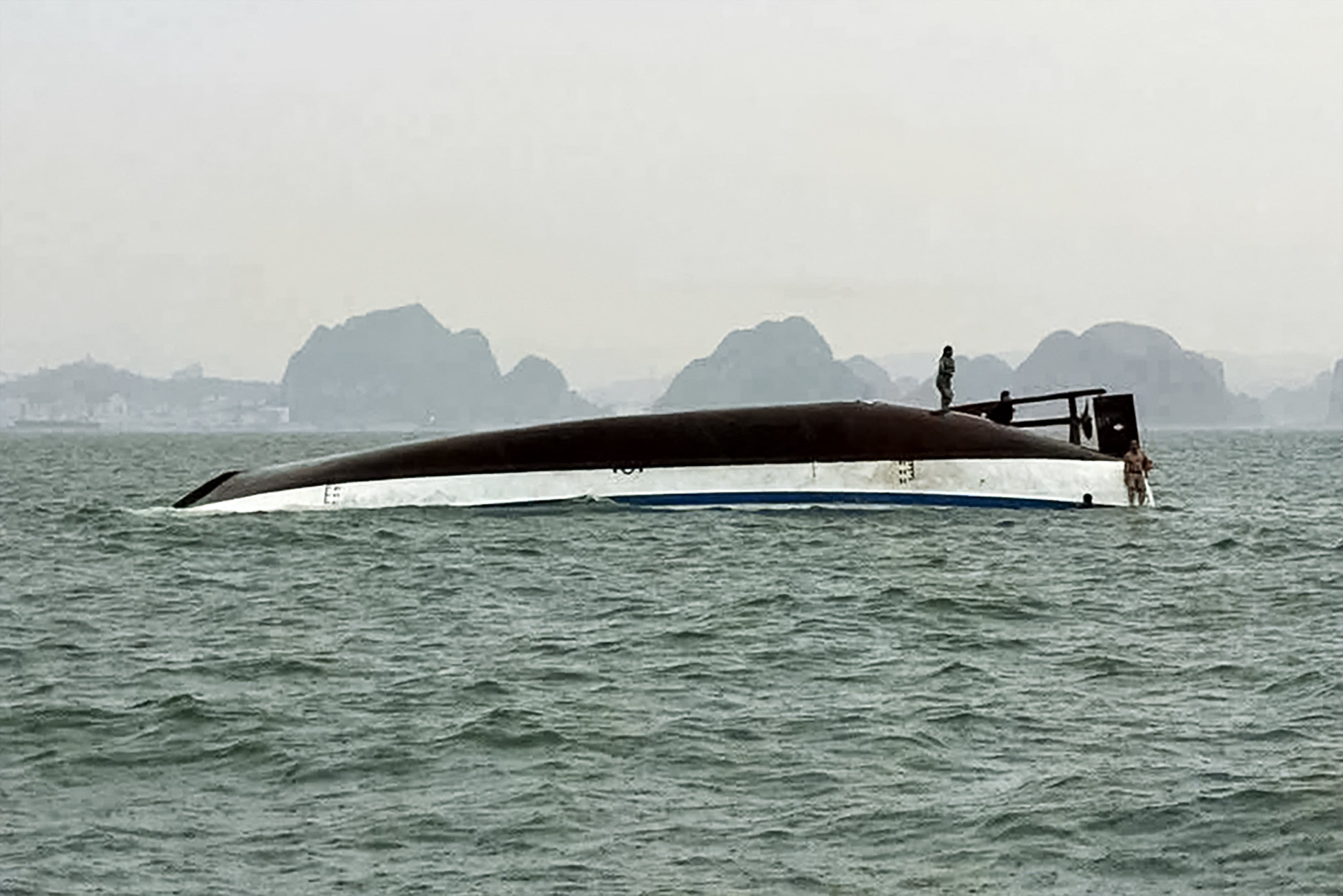 <p>Man stands on a tourist boat that capsized in Ha Long Bay in Vietnam</p>