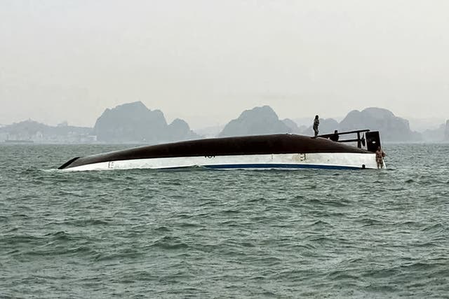 <p>Man stands on a tourist boat that capsized in Ha Long Bay in Vietnam</p>