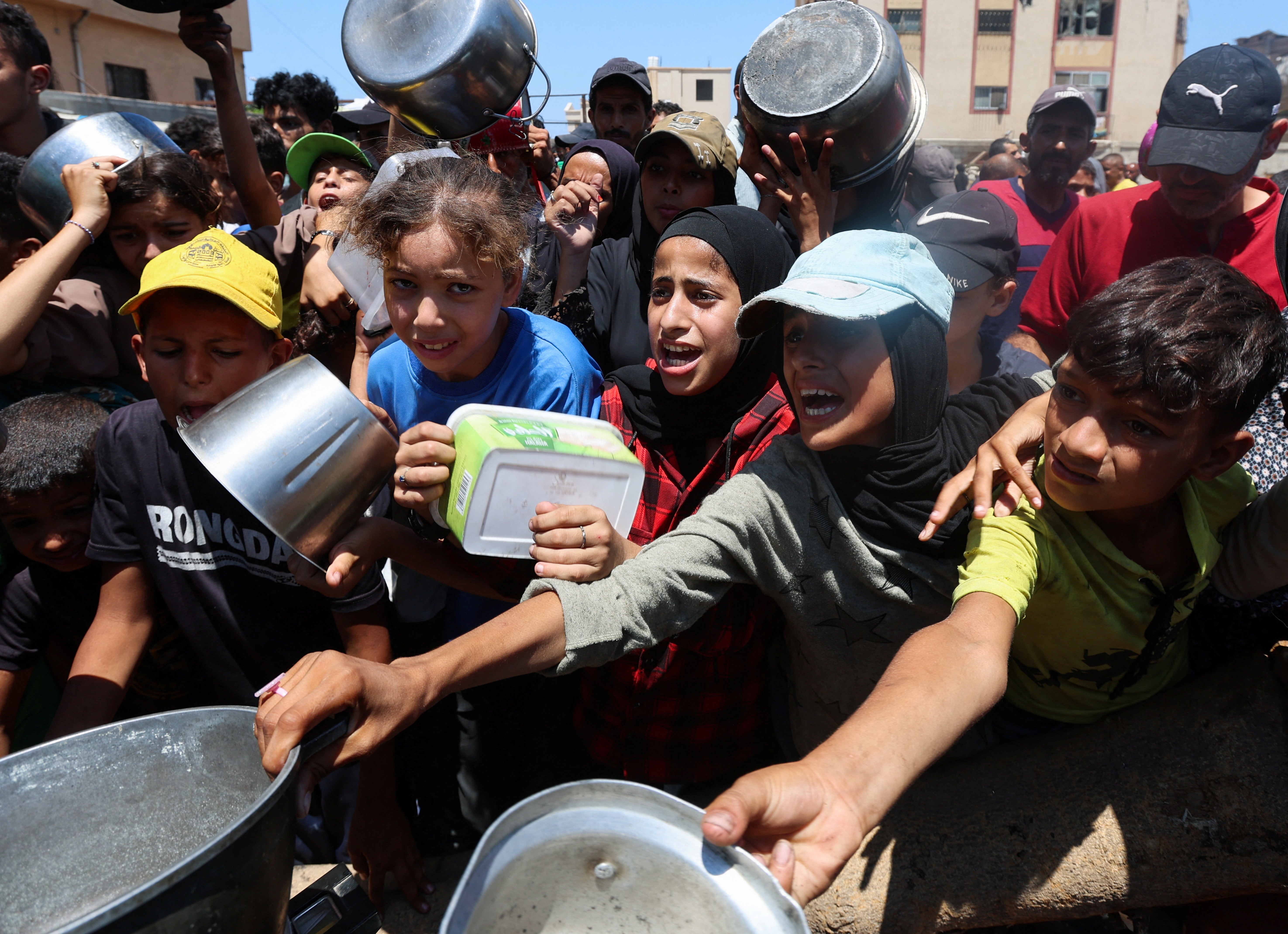 Palestinians gather to receive food from a charity kitchen, amid a hunger crisis, in Nuseirat on Sunday