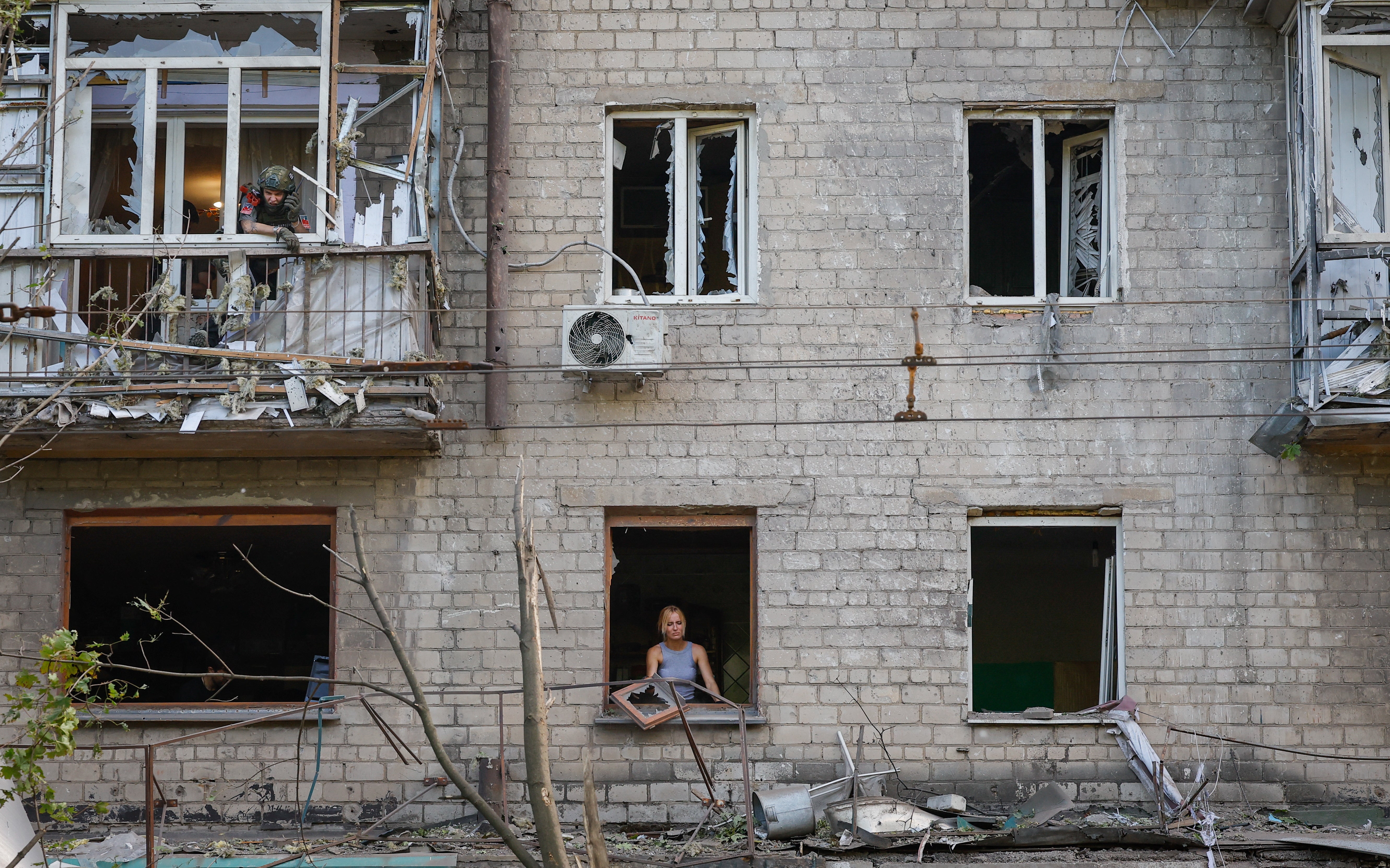 A woman removes broken glass from a window in the aftermath of recent shelling in Donetsk