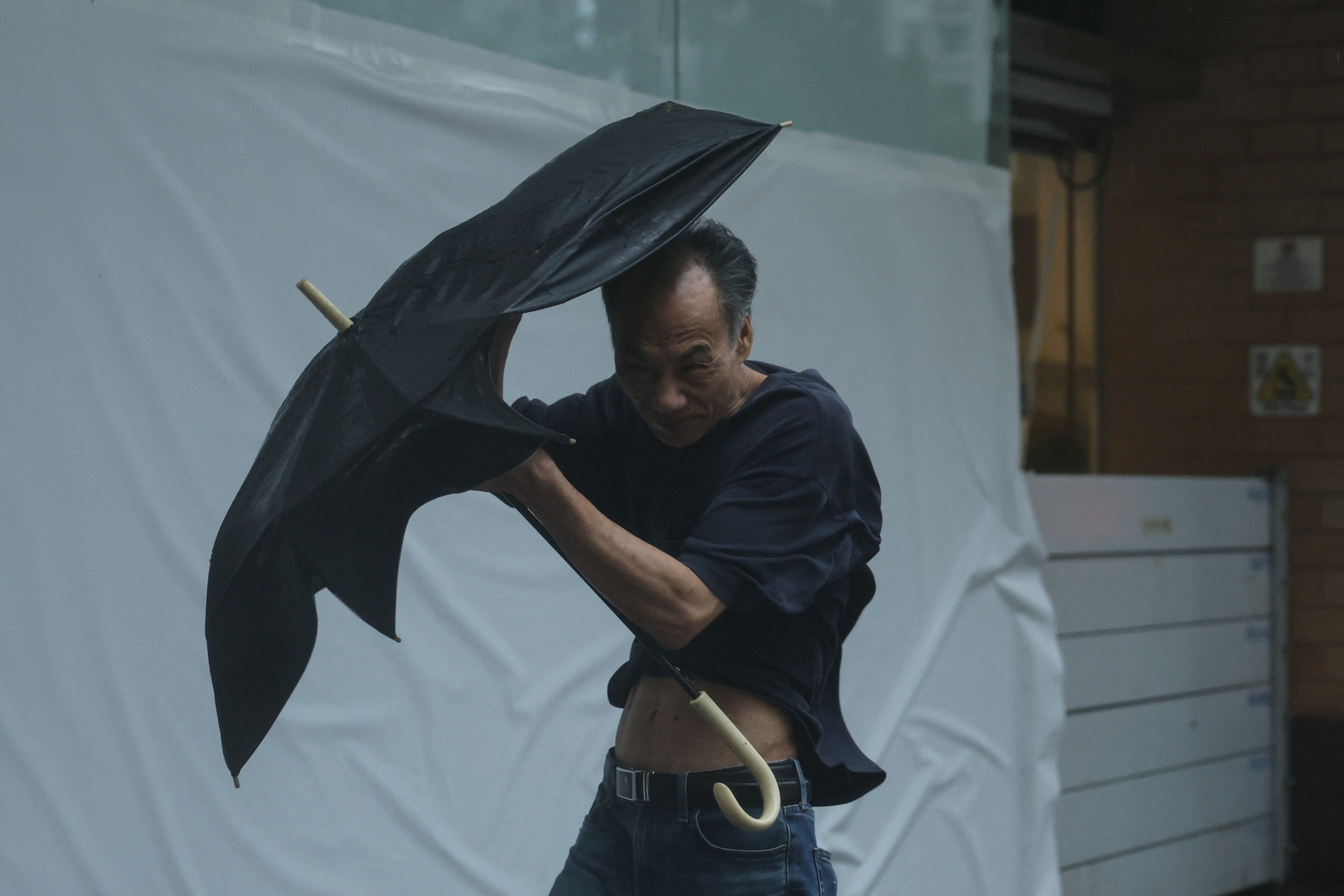 A man struggles while walking against strong wind as typhoon Wipha approaches in Hong Kong, China, on 20 July 2025