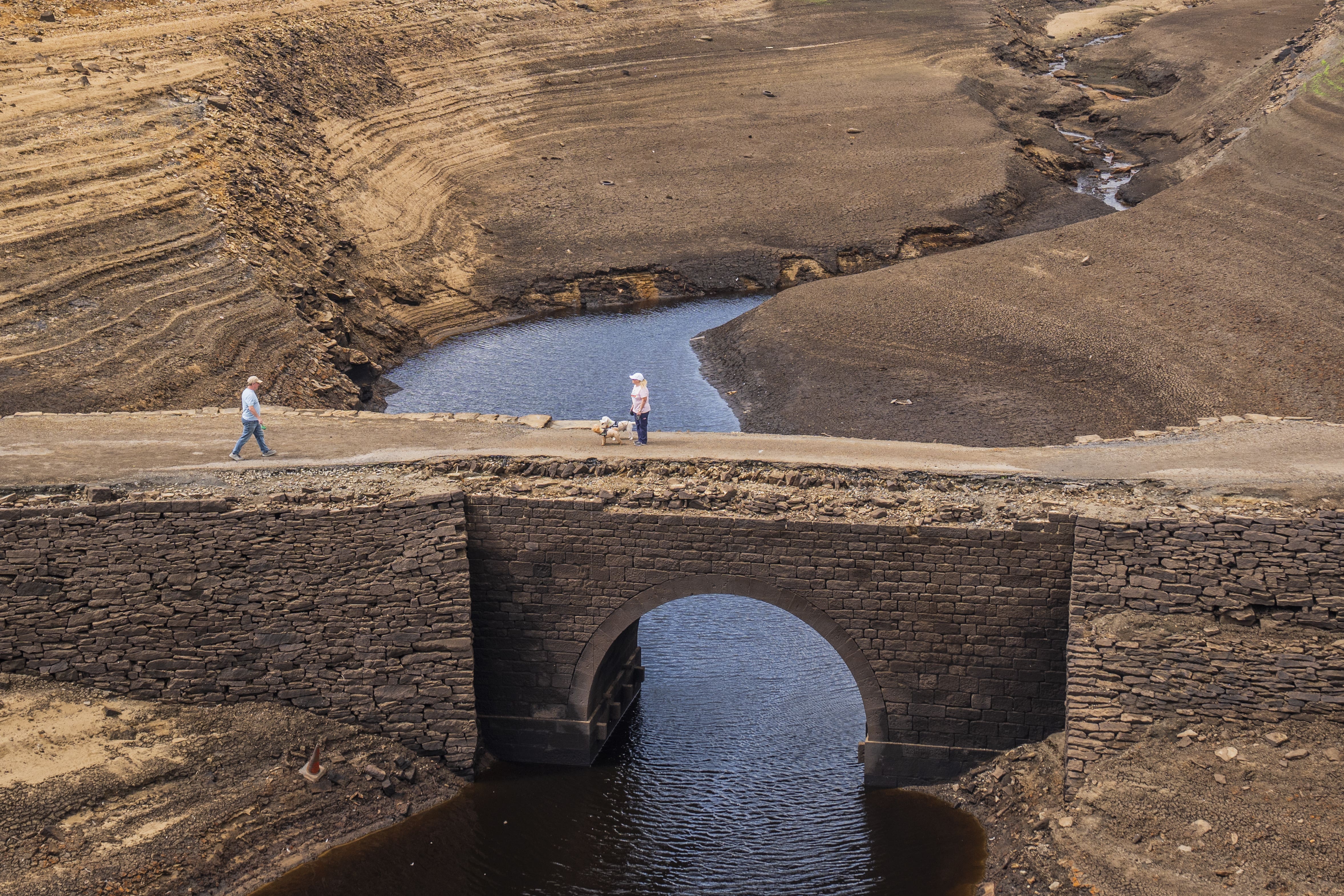 People walk over a bridge that is normally submerged by Baitings Reservoir in Ripponden, West Yorkshire. (Danny Lawson/PA)