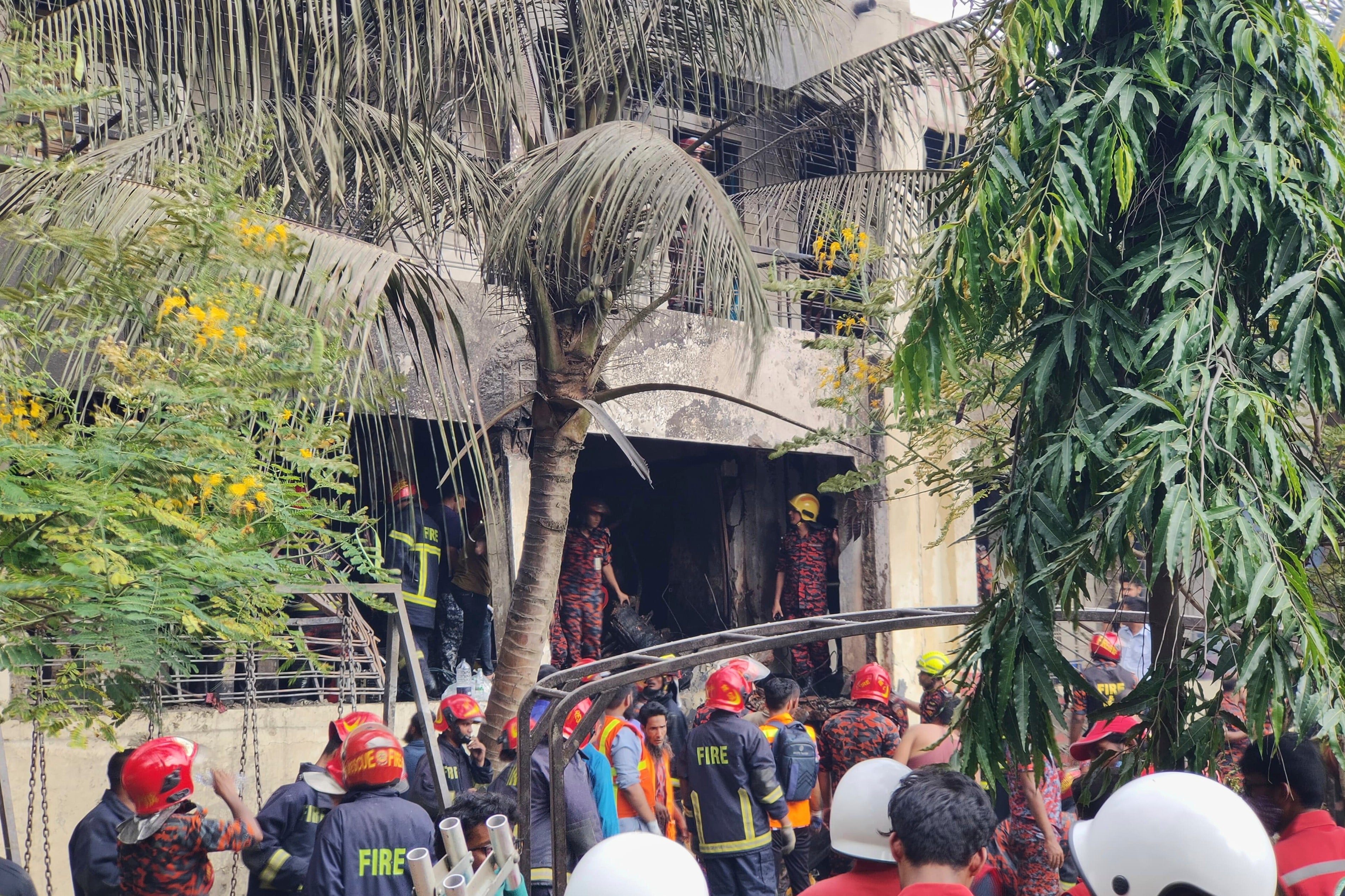 Firemen check the wreckage of a Bangladesh Air Force training aircraft that crashed onto a school campus in Dhaka, Bangladesh, Monday