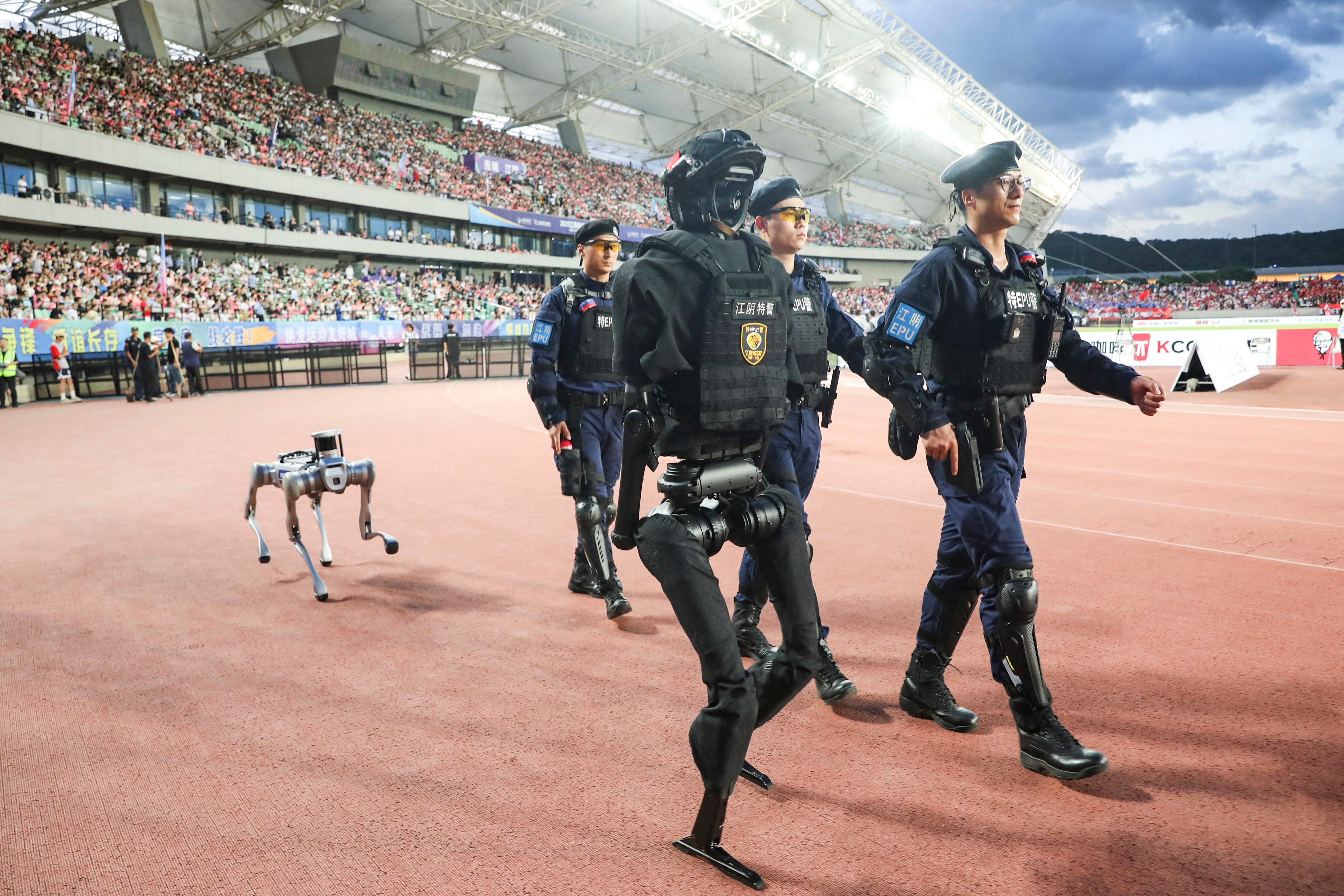 Police patrol with a humanoid robot and a robot dog during the Jiangsu City Football League match