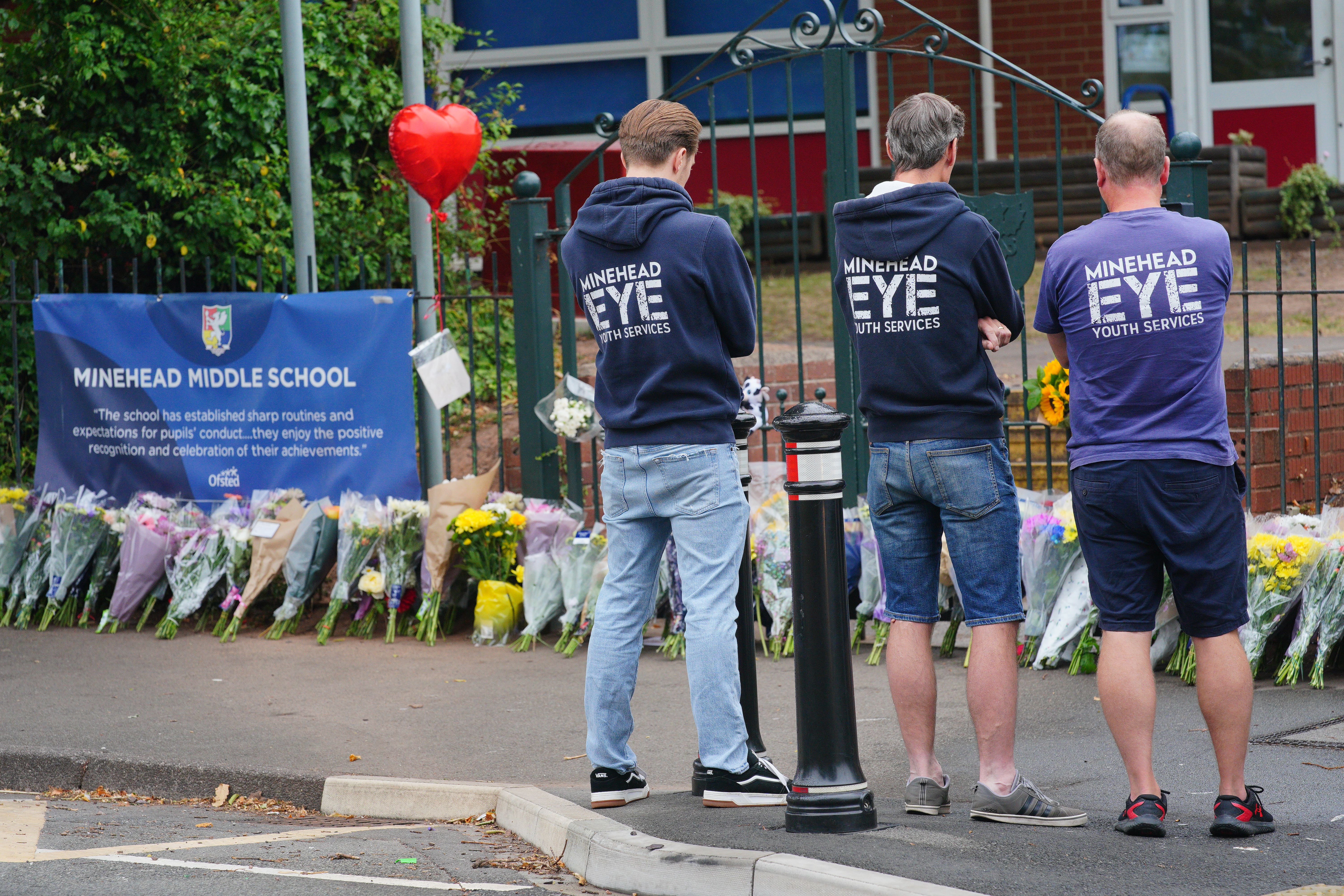 People look at floral tributes at the entrance to the Minehead Middle School