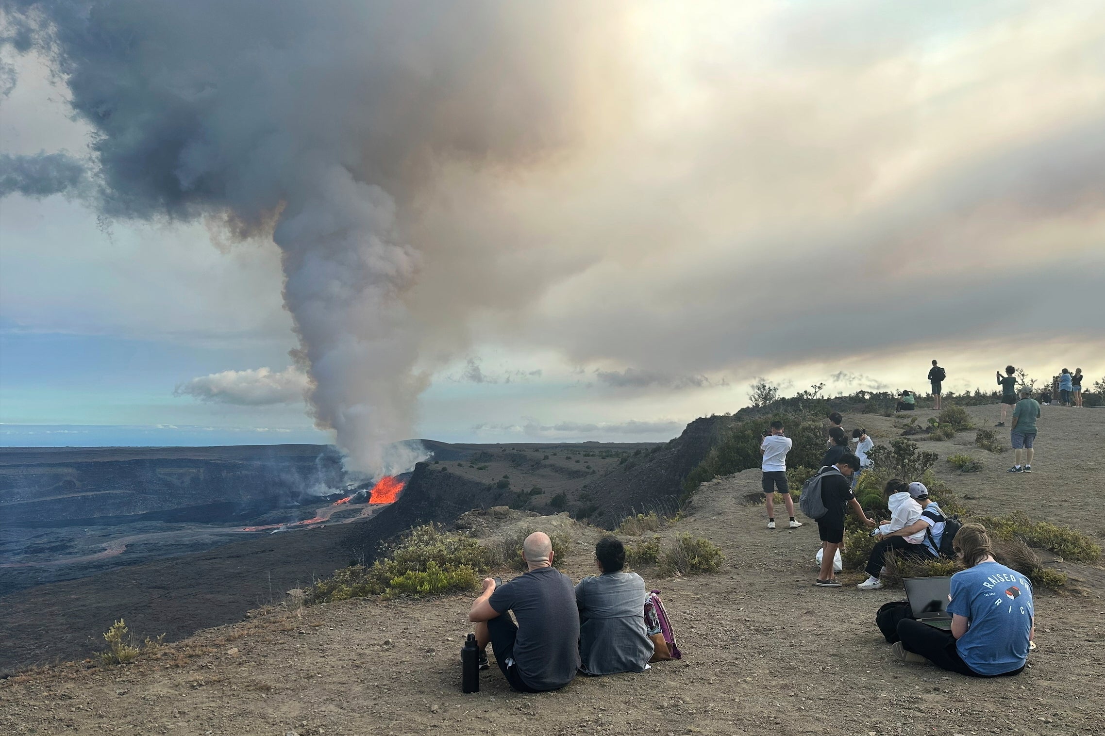 People watch the Kilauea volcano on Hawaii's Big Island as it erupts on Sunday, July 20, 2025
