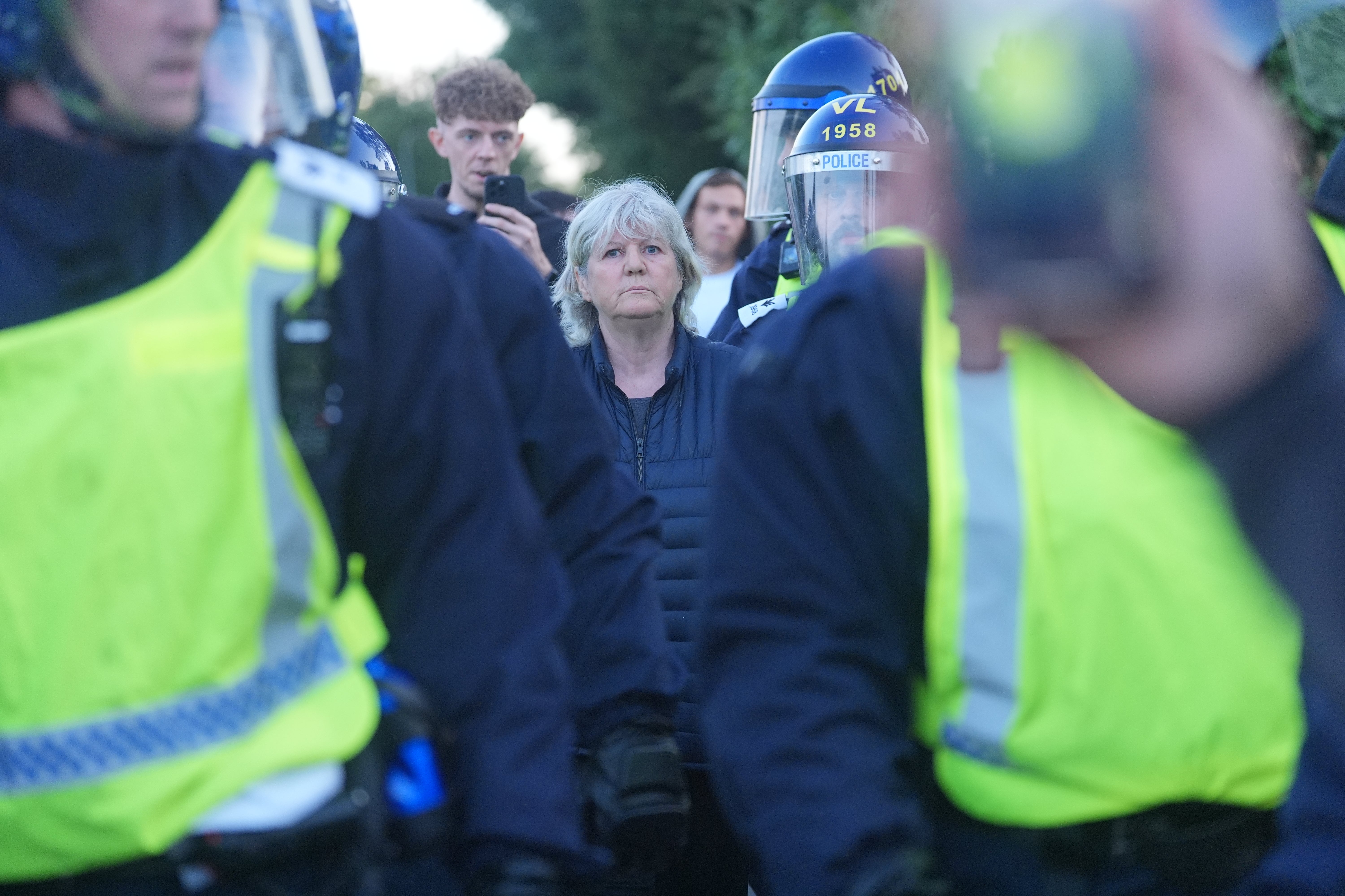Police officers escort a woman away from a demonstration for her own safety, after a protest outside the Bell Hotel in Epping, Essex.