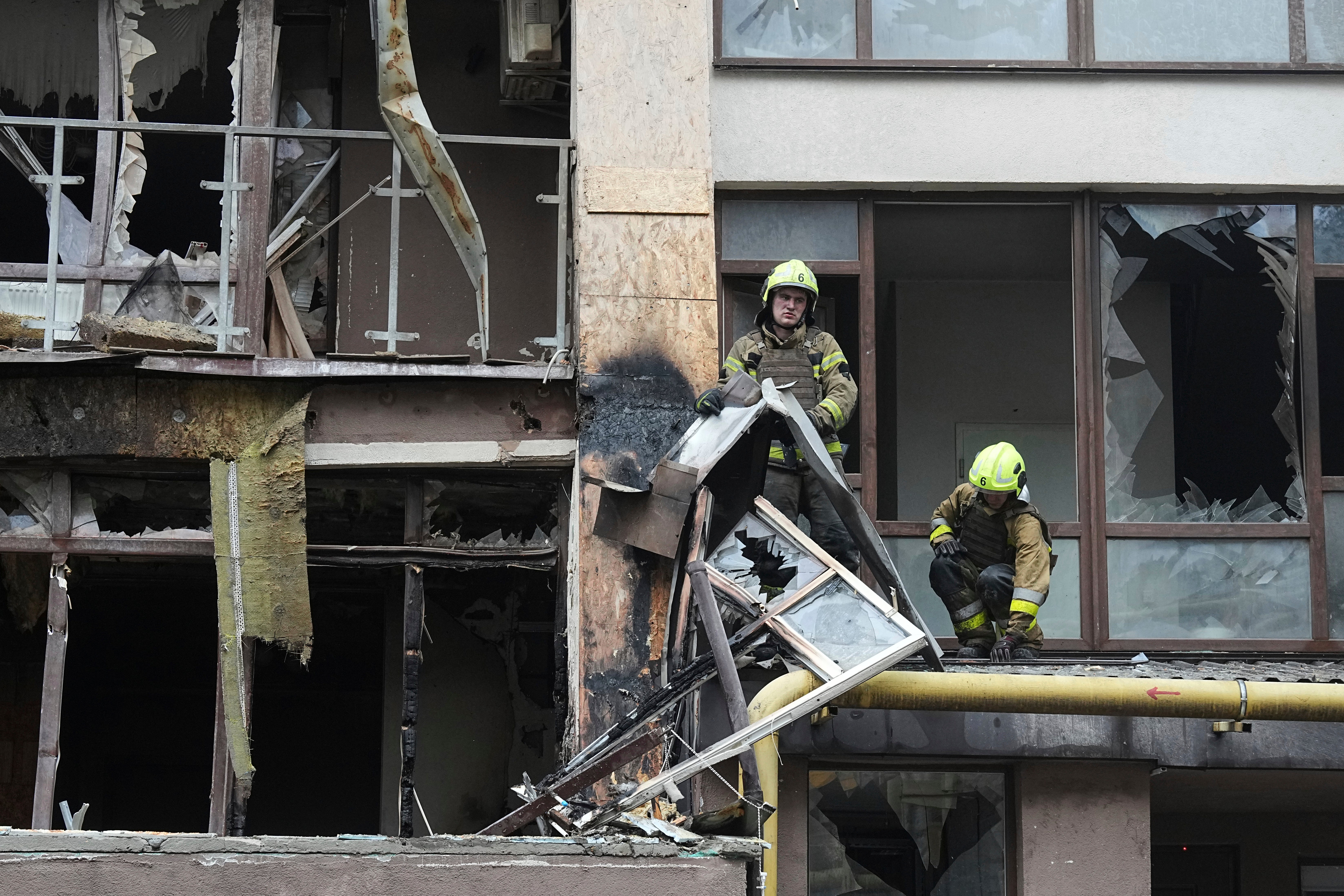 Firefighters work in a destroyed apartment building after a Russian attack in Kyiv on Monday