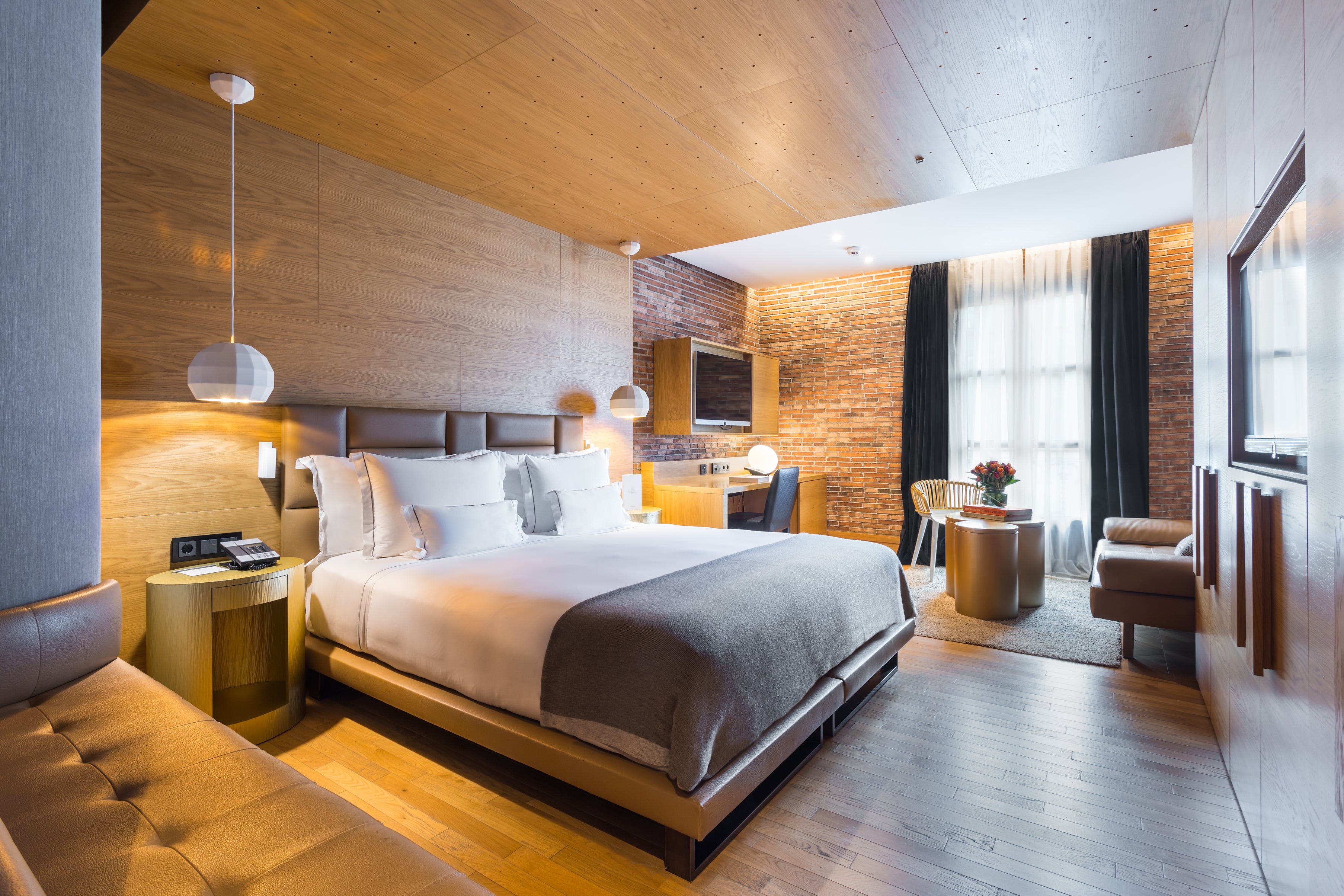 Red brick walls and custom oak furniture completes rooms at Monument Barcelona
