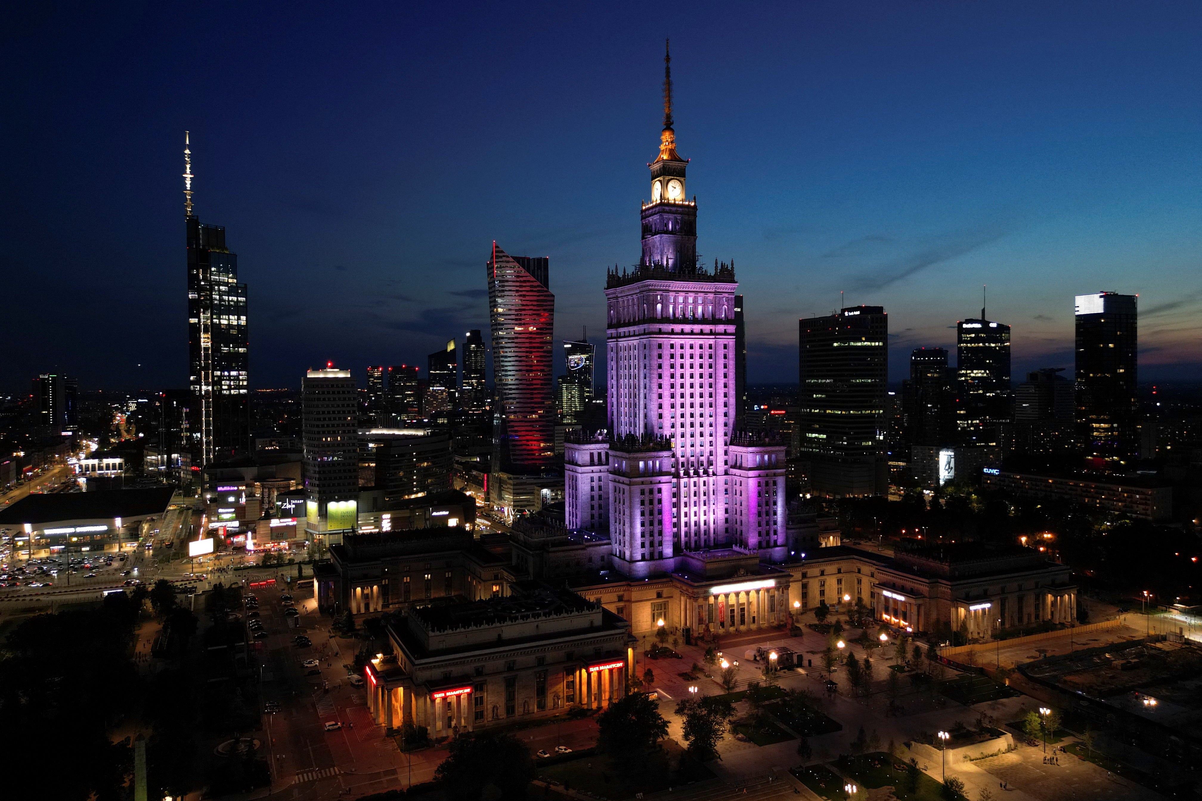 A drone view shows Warsaw’s skyline at night, with illuminated skyscrapers and the Palace of Culture and Science in Warsaw, Poland