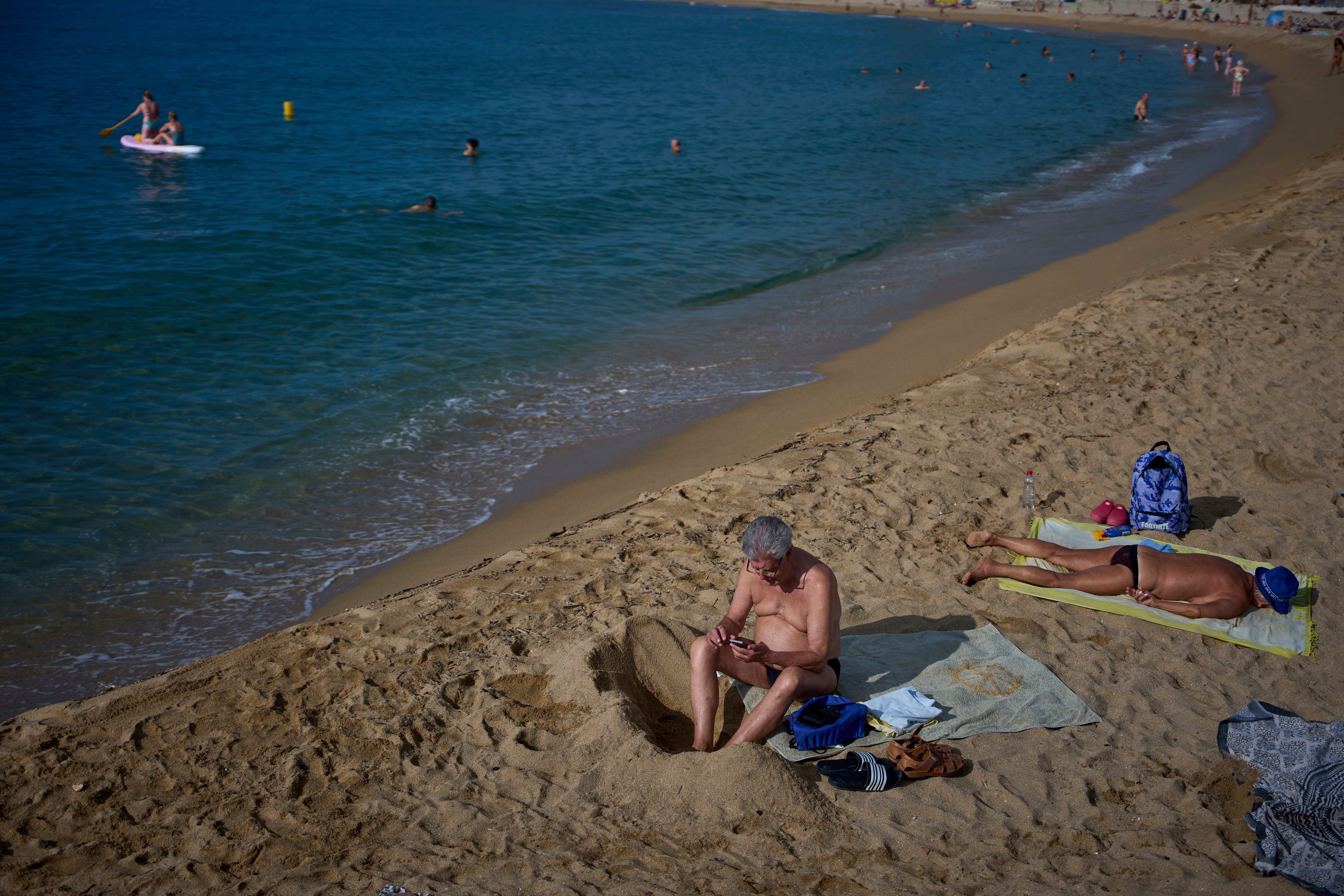 Sunbathers relax on a beach in Barcelona, Spain, Tuesday, July 22, 2025. (AP Photo/Emilio Morenatti)