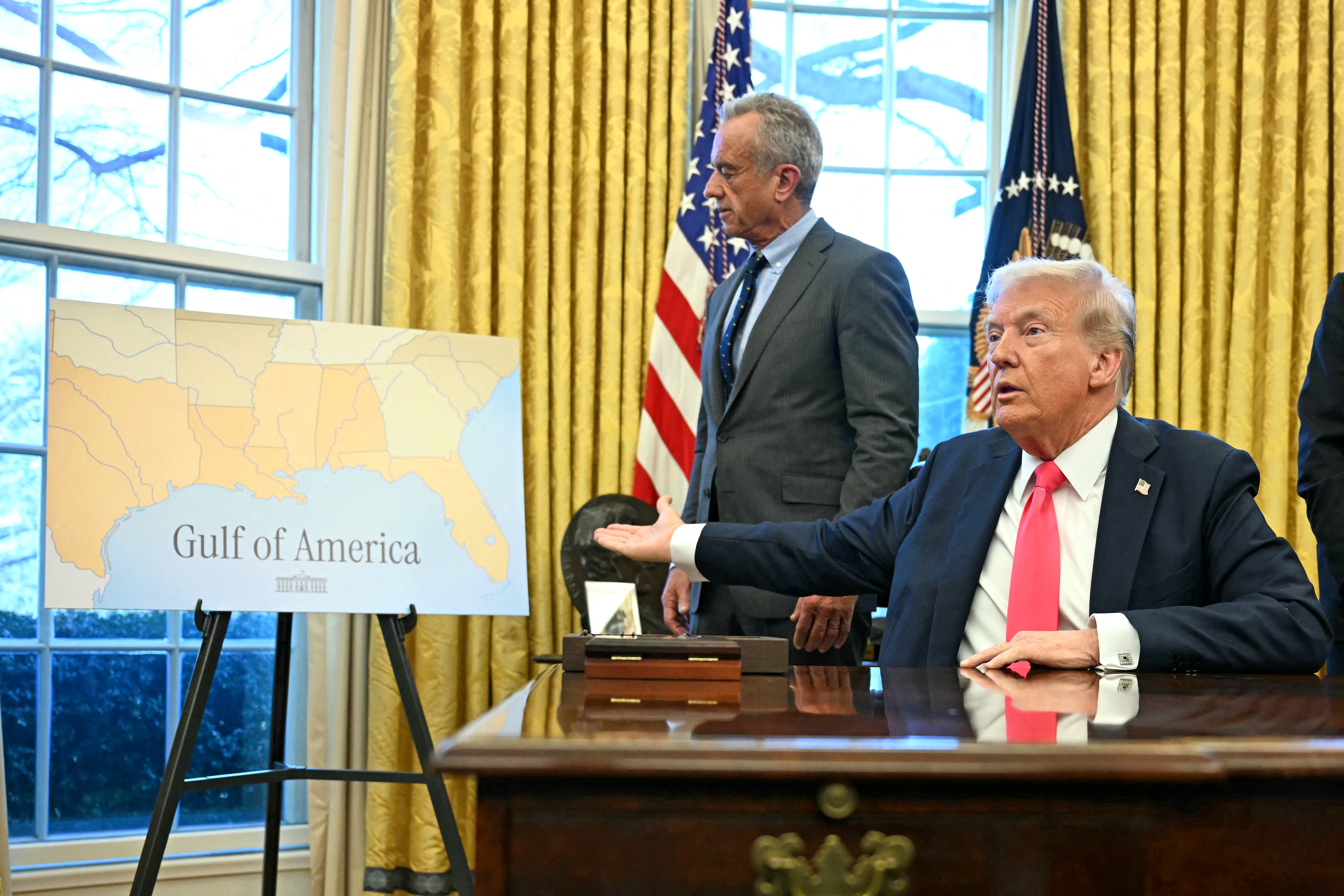 President Donald Trump gestures to a 'Gulf of America' graphic in the Oval Office. The U.S. Geological Survey, a federal agency in charge of the country's geographic names, told its staff not to respond to journalists' questions after Trump first announced the change, a new report reveals.