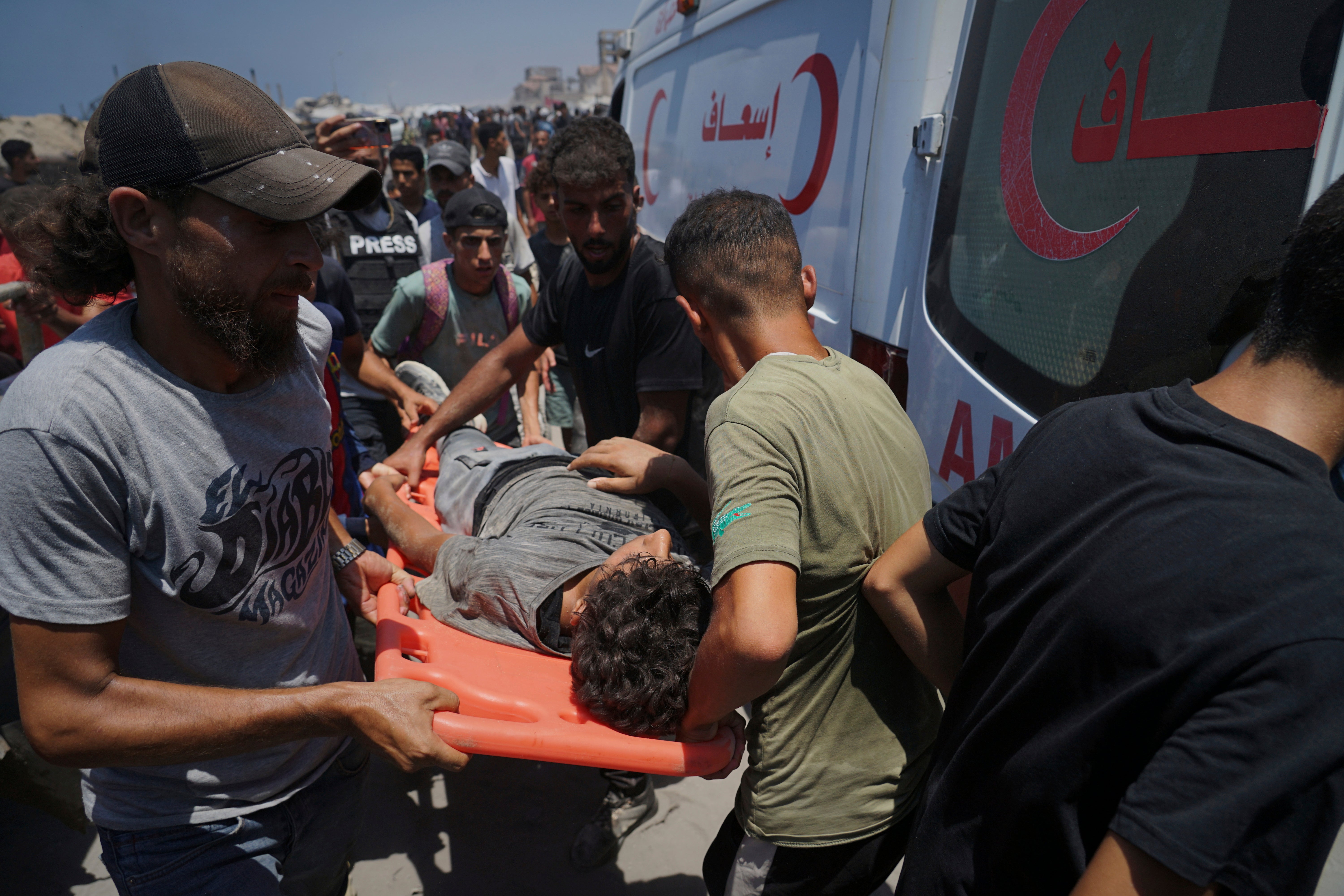 Injured Palestinians are transferred to an ambulance after being wounded while waiting for aid