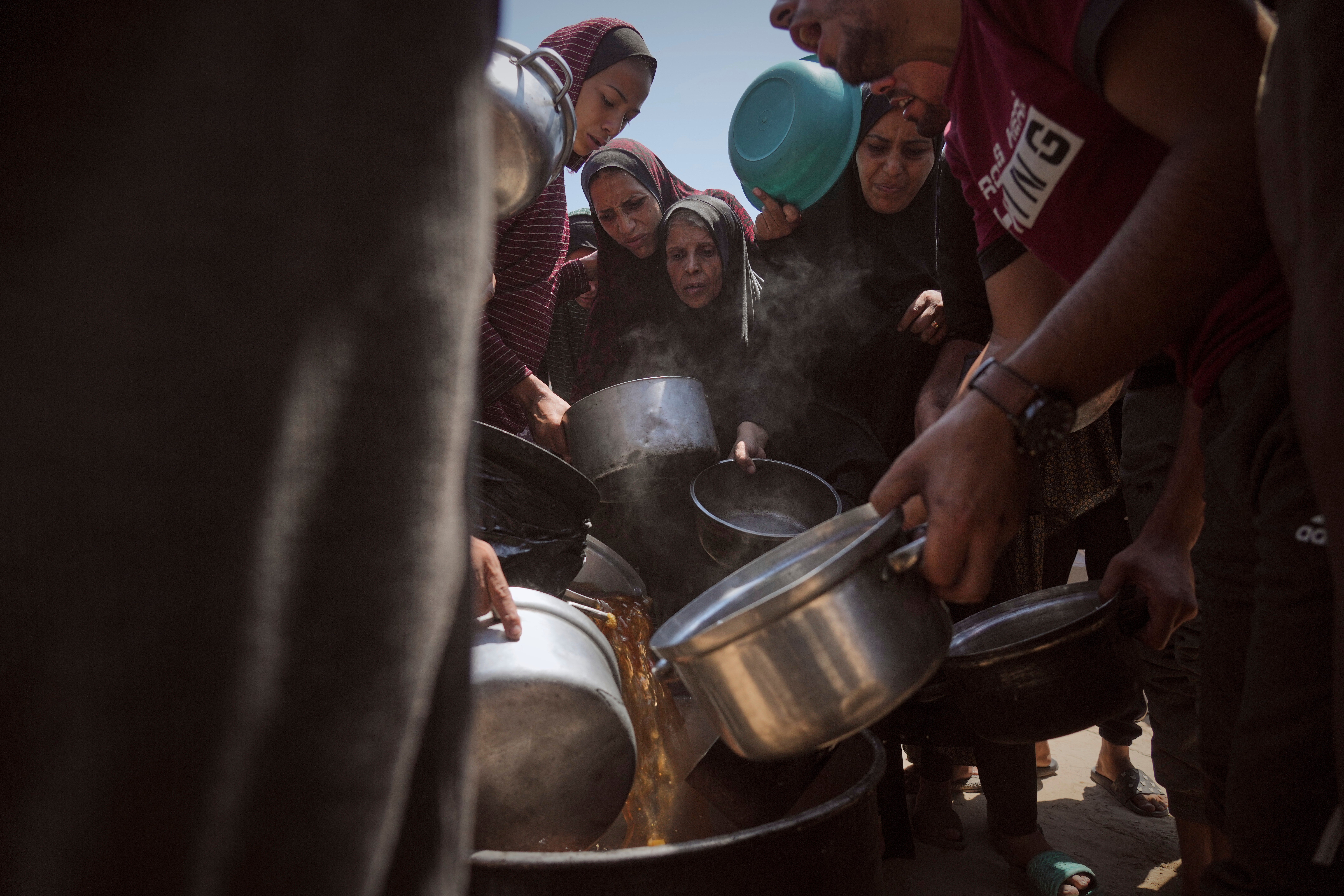 Displaced Palestinians receive donated food at a community kitchen in Gaza City, northern Gaza Strip
