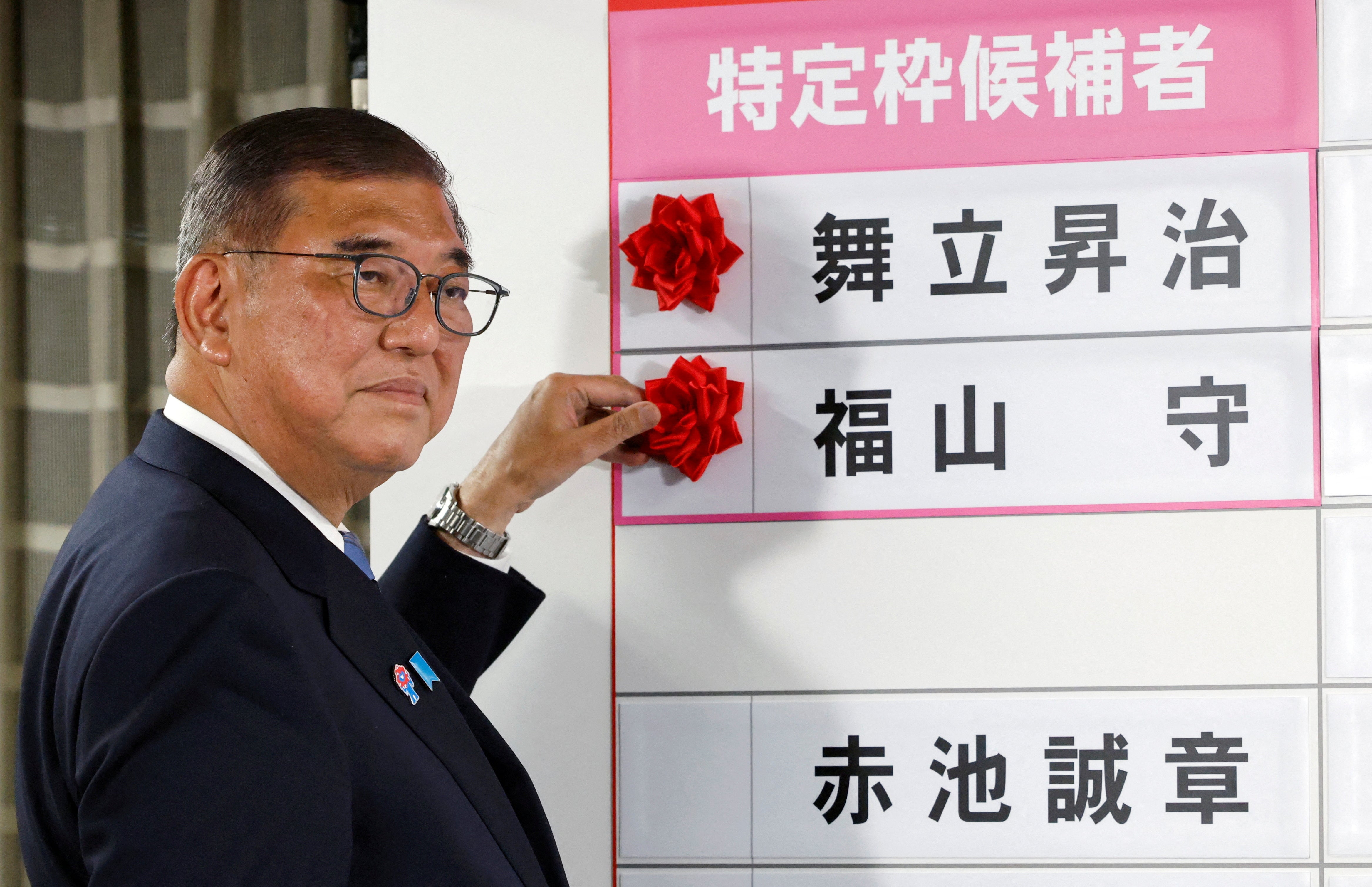 <p>Shigeru Ishiba, Japan's Prime Minister and president of the ruling Liberal Democratic Party (LDP), places a red paper rose on the name of an elected candidate at the LDP headquarters, on the day of Upper House election, in Tokyo, Japan July 20, 2025. Franck Robichon/Pool via REUTERS/File Photo</p>