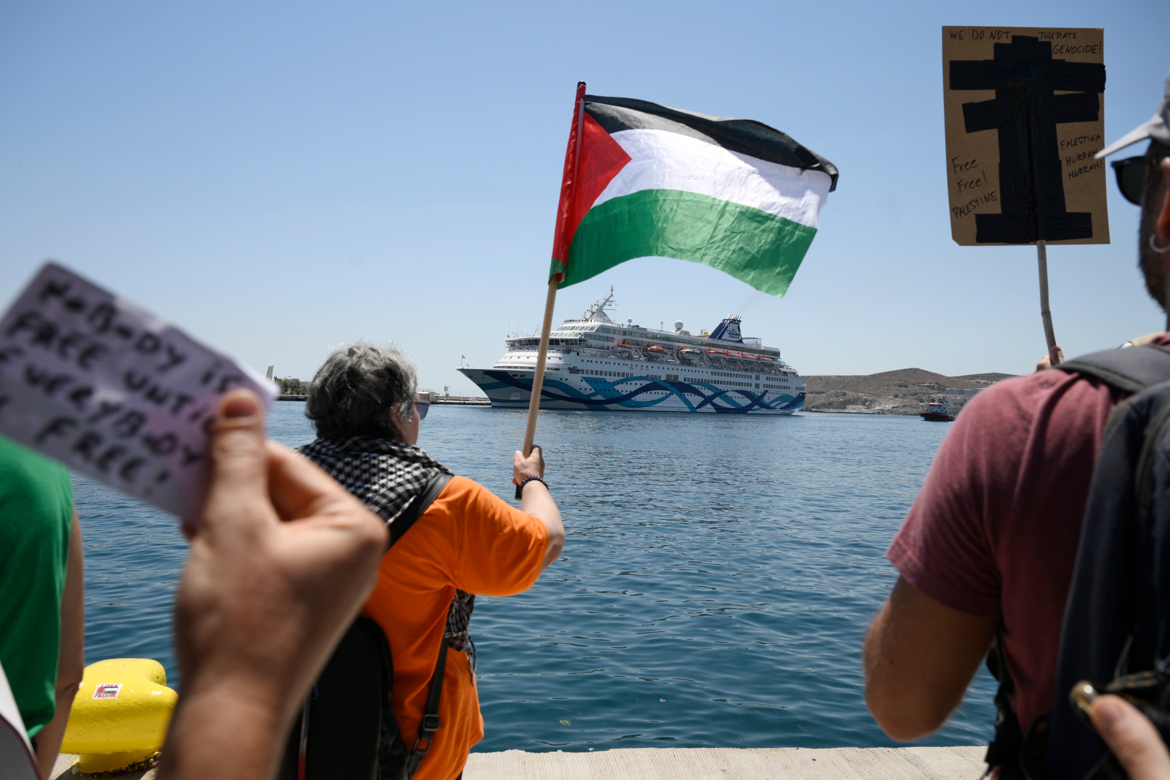 A protester waves a Palestinian flag as a cruise ship nears the Greek island of Syros
