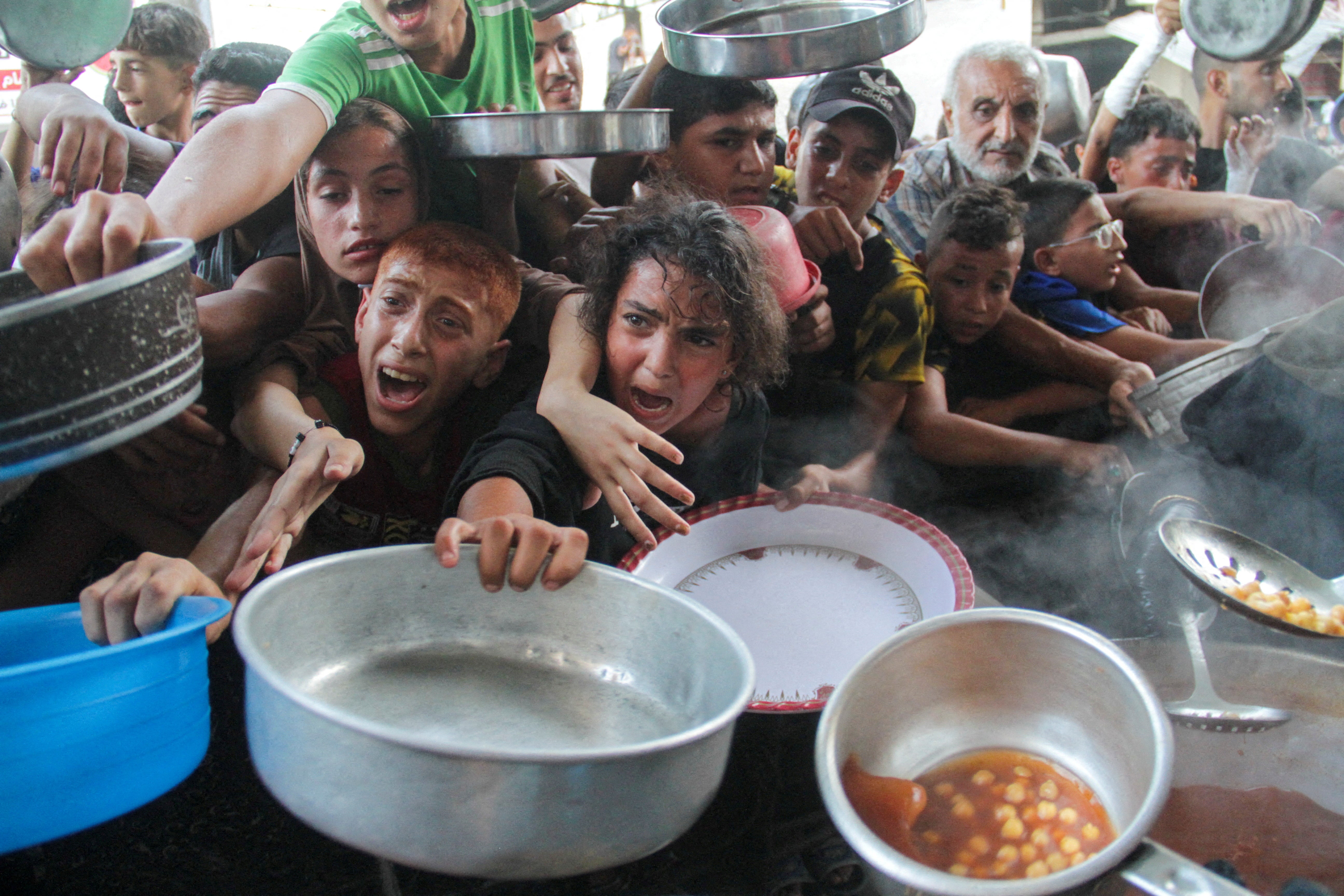 Palestinians gather to receive food cooked by a charity kitchen amid the Israel-Hamas conflict