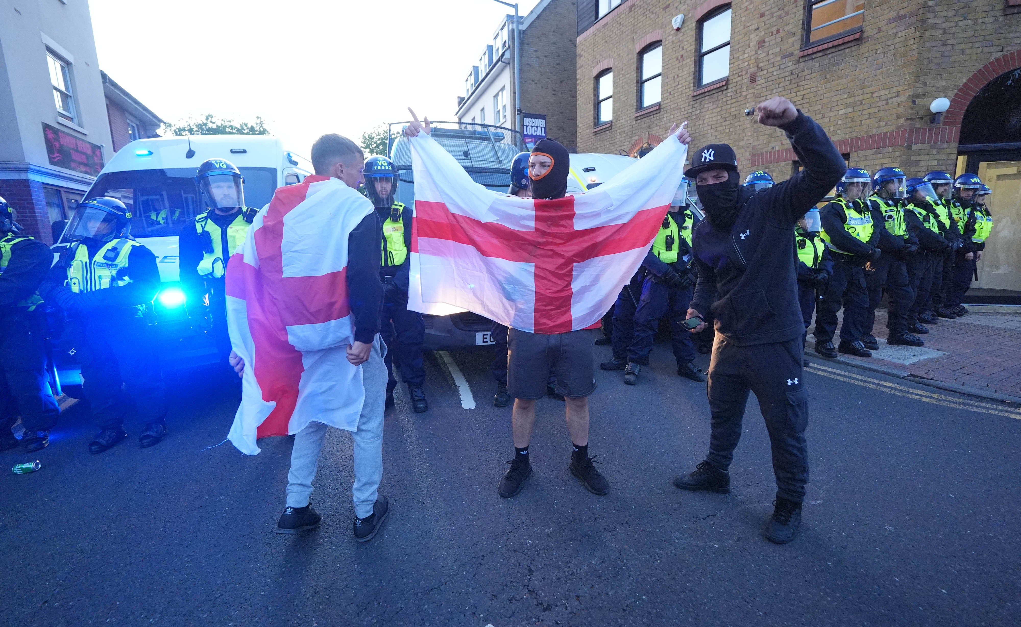 Protesters hold up a flag of St George after a protest in Epping
