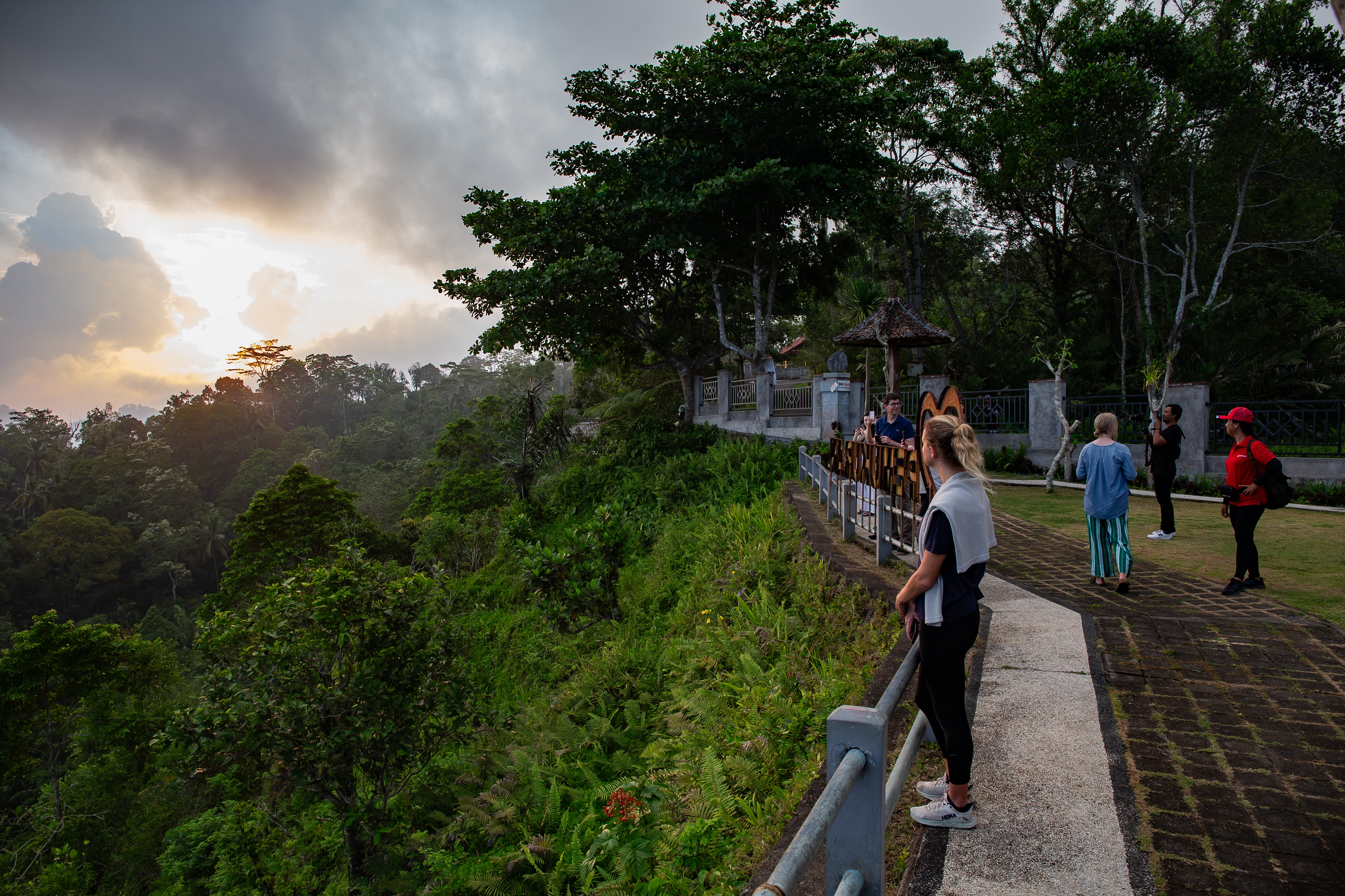 The village sits above a lush green canopy of forest reaching out to the ocean below