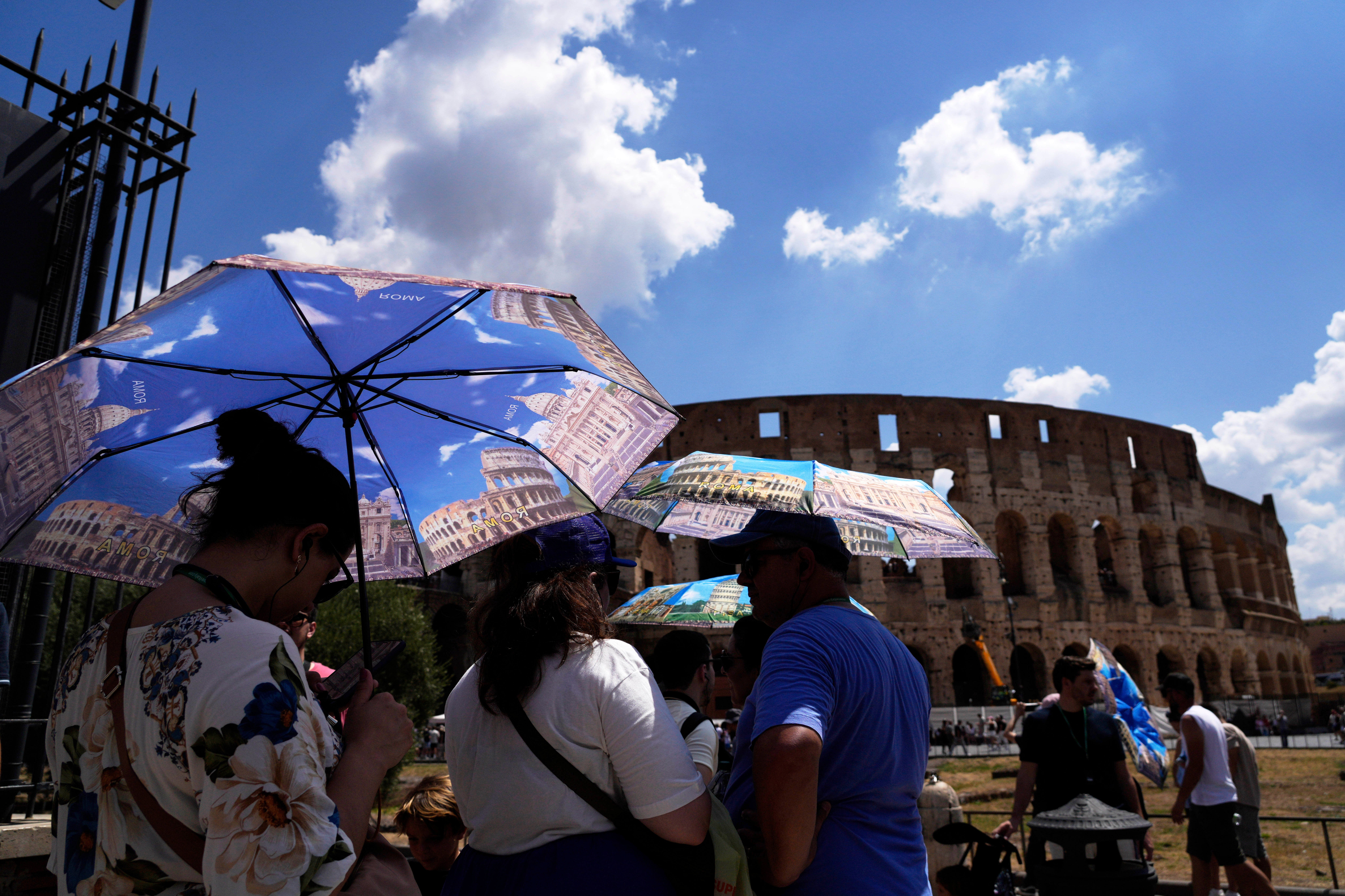 Tourists use umbrellas to shelter from the heat as they line up for a tour of the Forum in Rome, on Tuesday, July 22, 2025. (AP Photo/Gregorio Borgia)