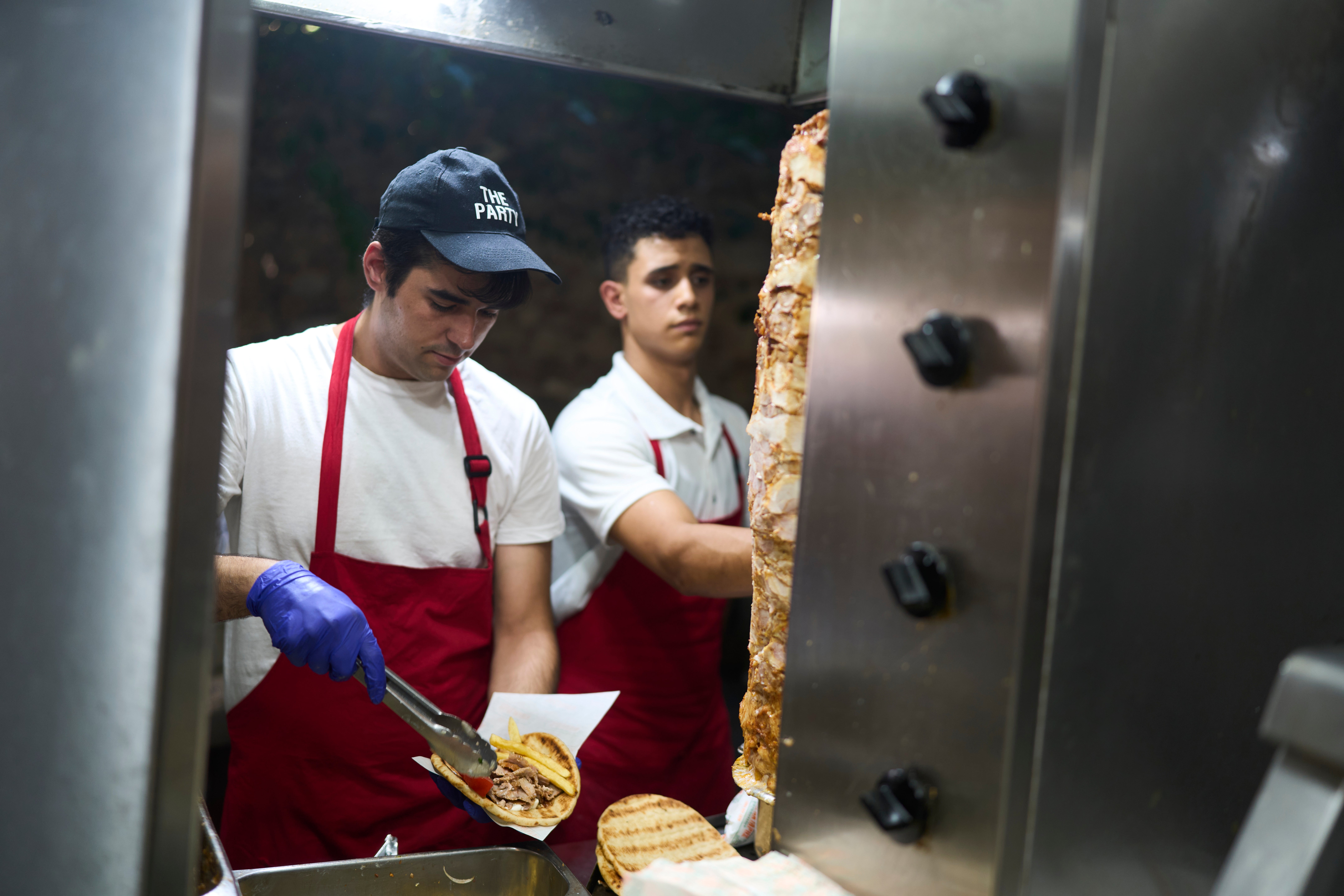 Grill cook Thomas Siamandas makes traditional souvlaki in a restaurant in the central Monastiraki district during a hot day in Athens on Wednesday, July 16, 2025. (AP Photo/Petros Giannakouris)